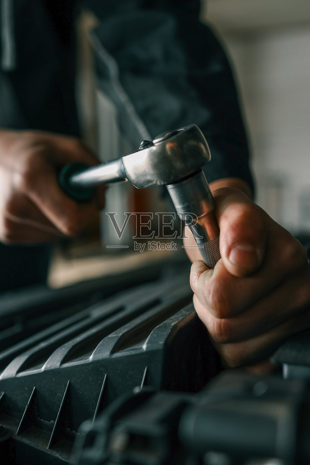 机械师在专业车间使用棘轮扳手紧固汽车发动机上的螺栓照片摄影图片