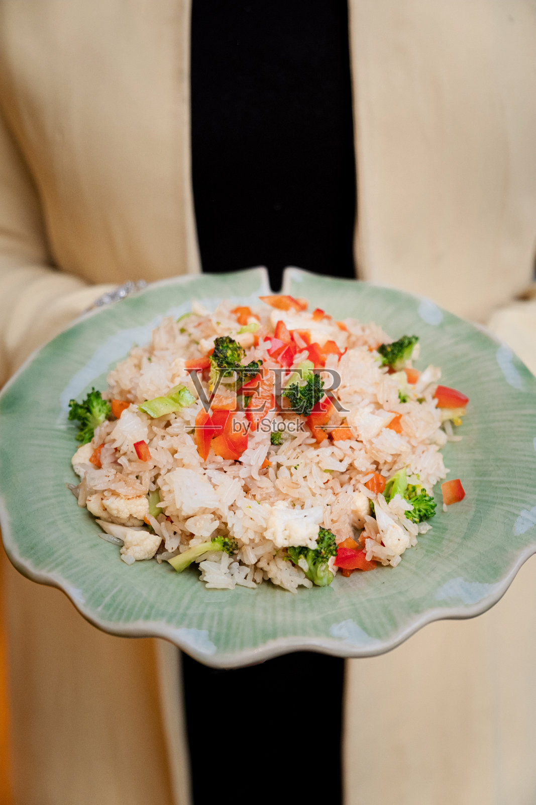 色彩鲜艳的泰式炒饭，搭配新鲜蔬菜，结合了切丁的番茄和西兰花，散发着香草的气息，置身于传统的泰国餐厅环境中。照片摄影图片