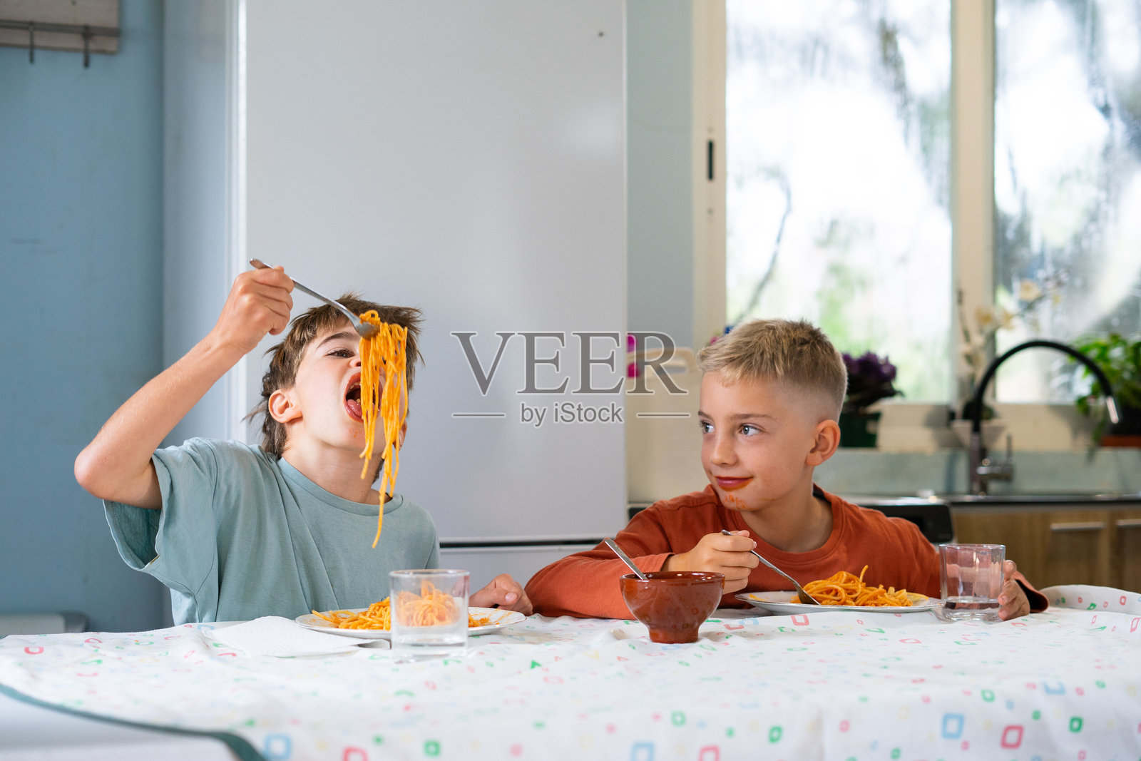 孩子们在家里开心地吃意大利面配番茄酱照片摄影图片