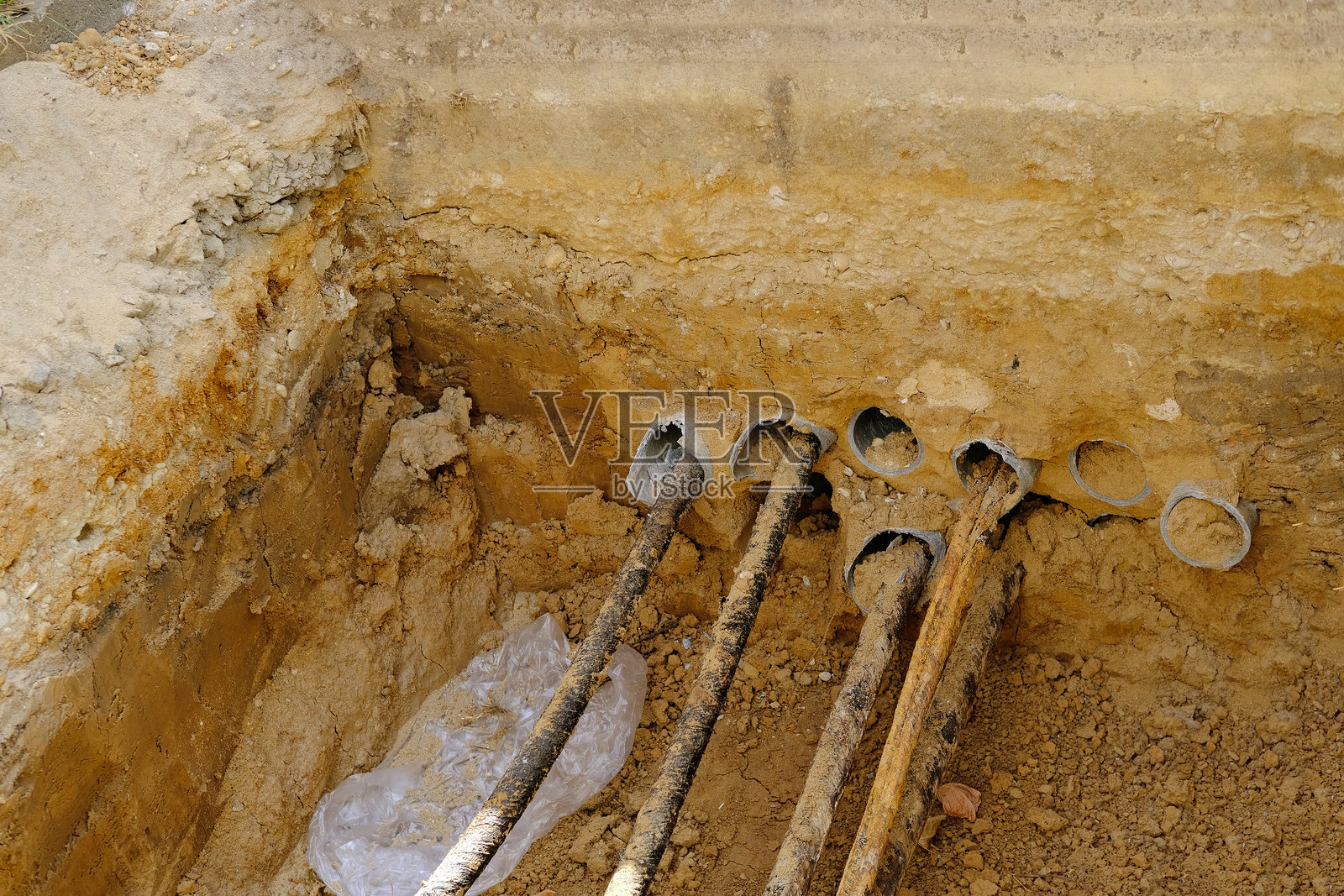 挖掘的坑道展示了水管和电缆，展示了地下基础设施的修复工作，修复城市通信。照片摄影图片