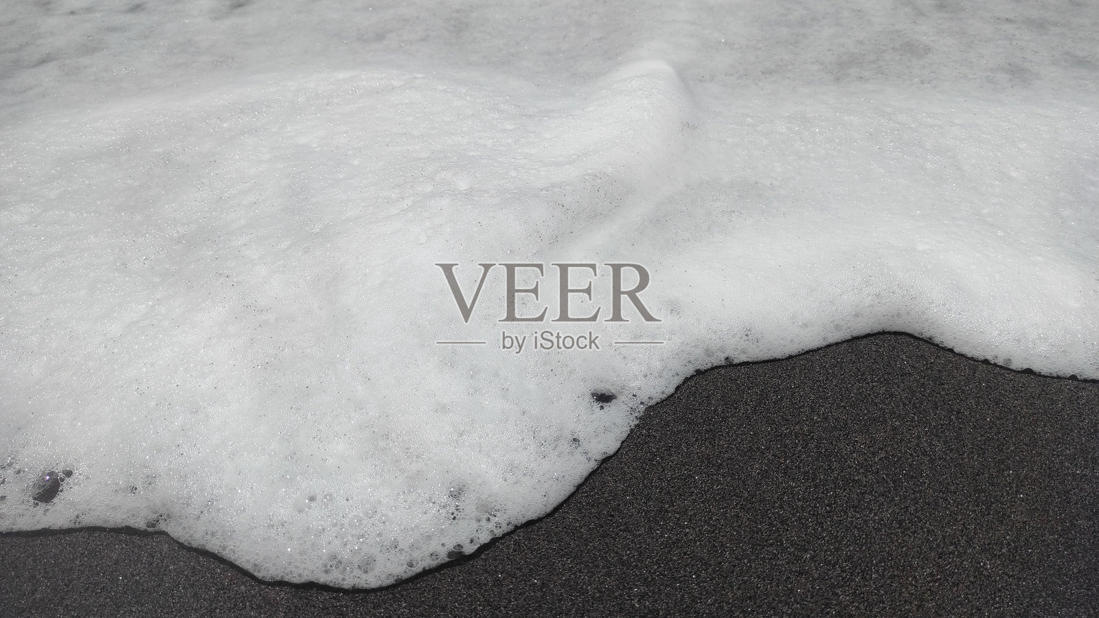 黑沙滩上的泡沫浪花特写照片摄影图片