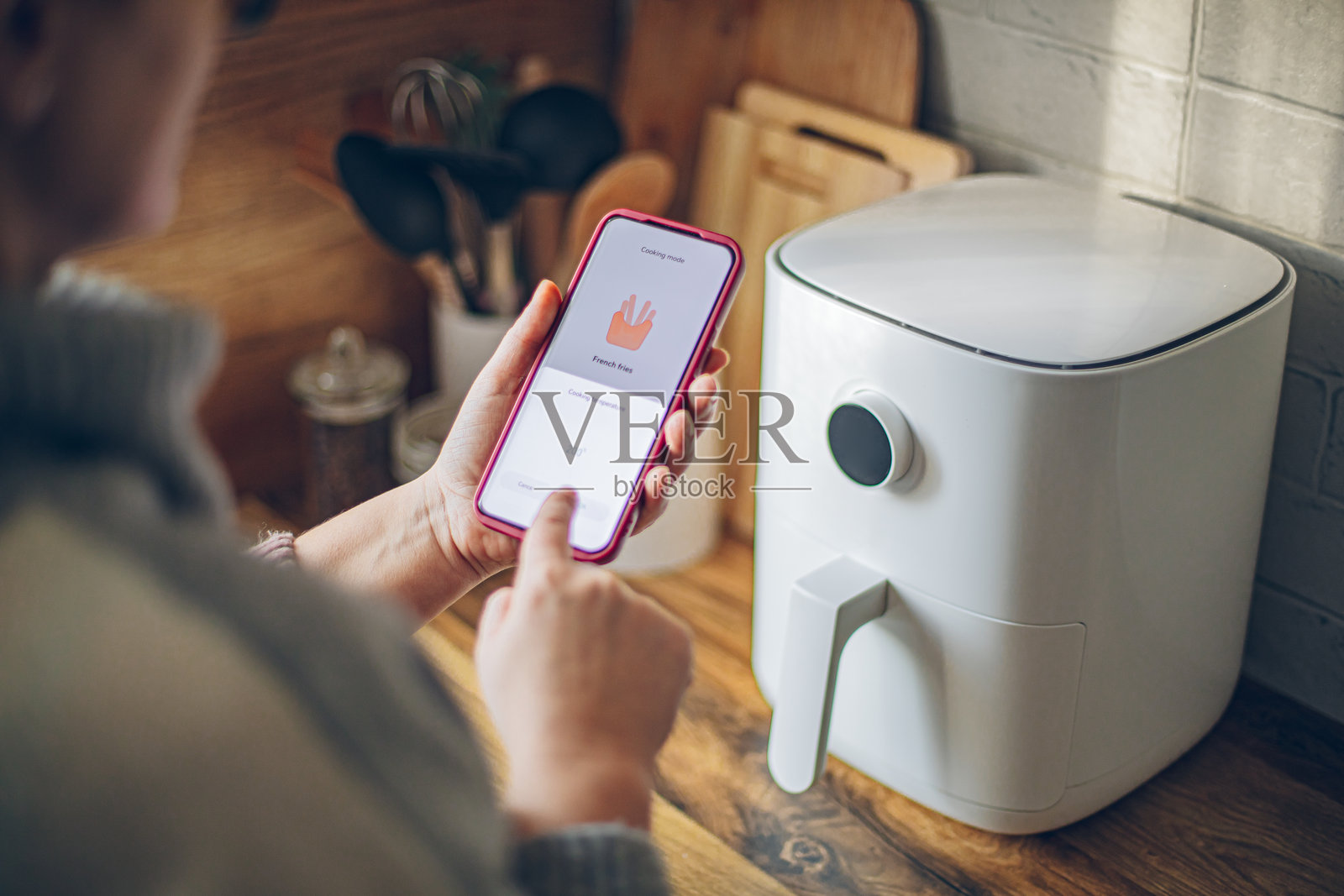 女性使用智能手机应用程序控制智能厨房电器照片摄影图片