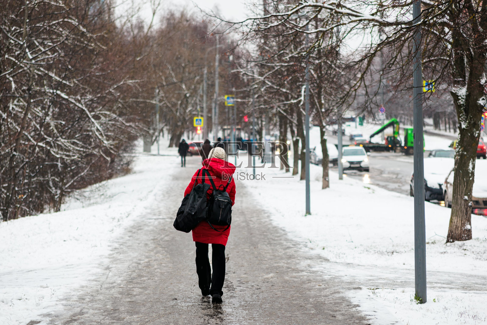 在莫斯科,一名女性在潮湿的天气中走在街上。街道上有泥泞、雨水和雪。照片摄影图片