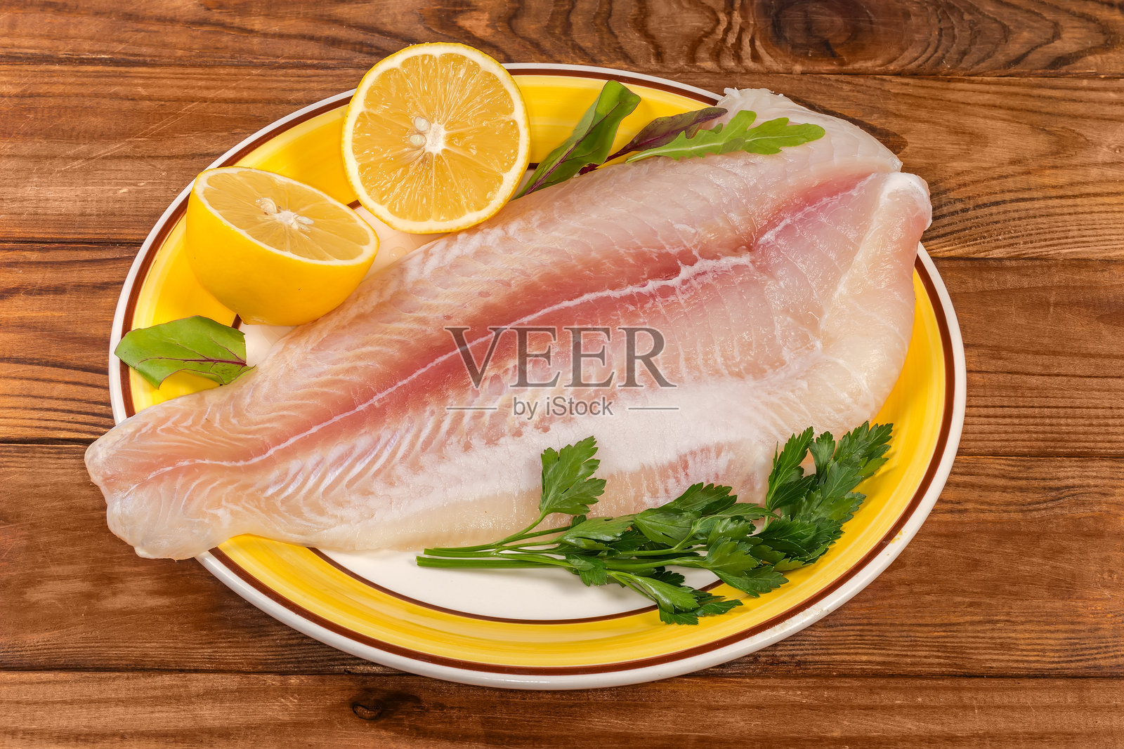 黄盘上的鲶鱼片，旁边放着柠檬，摆放在乡村风格的桌子上照片摄影图片