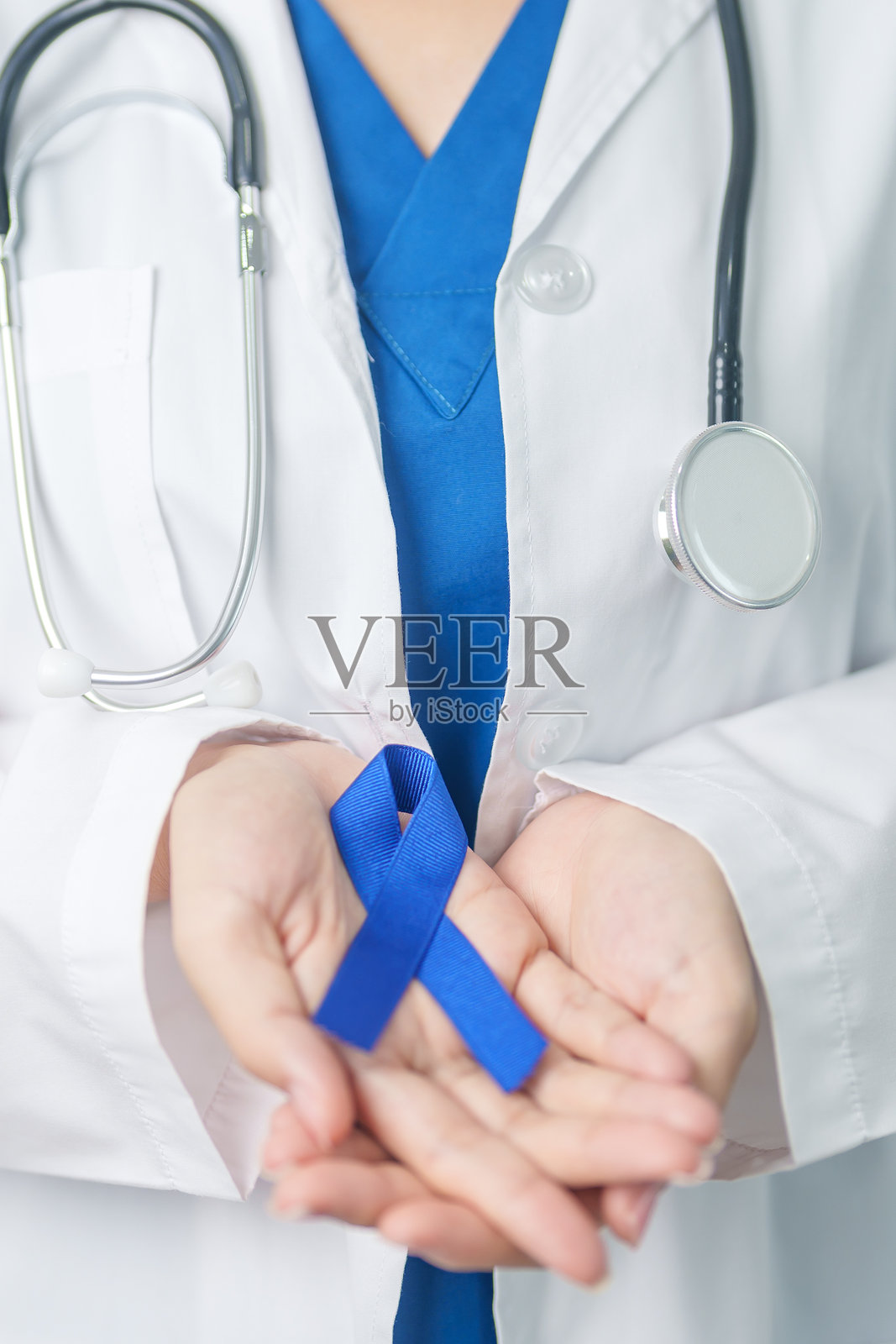 三月是结直肠癌意识月，医生手持深蓝色丝带以支持癌症患者。医疗、希望与世界癌症日的概念。照片摄影图片