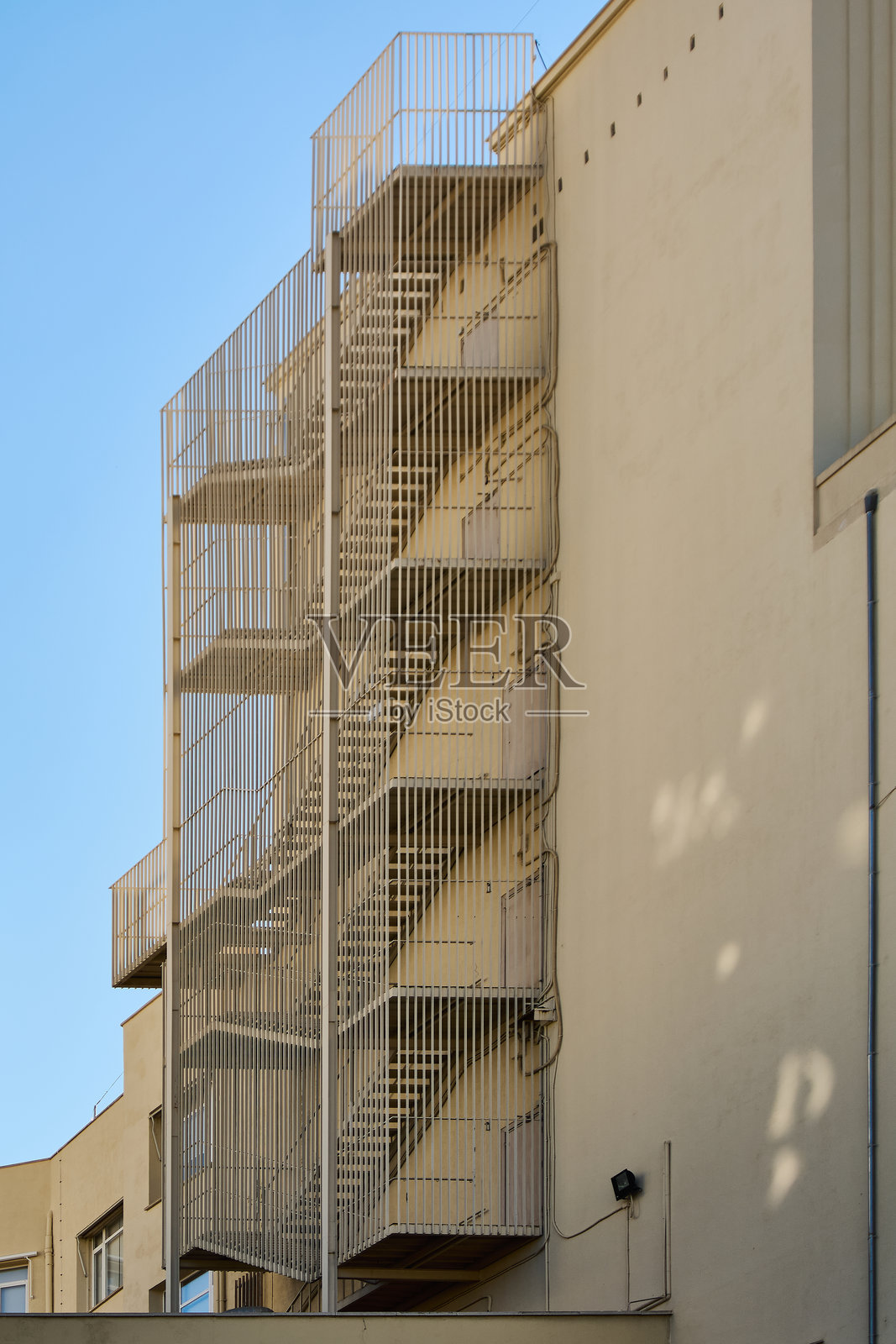 米色建筑上的金属消防逃生楼梯照片摄影图片