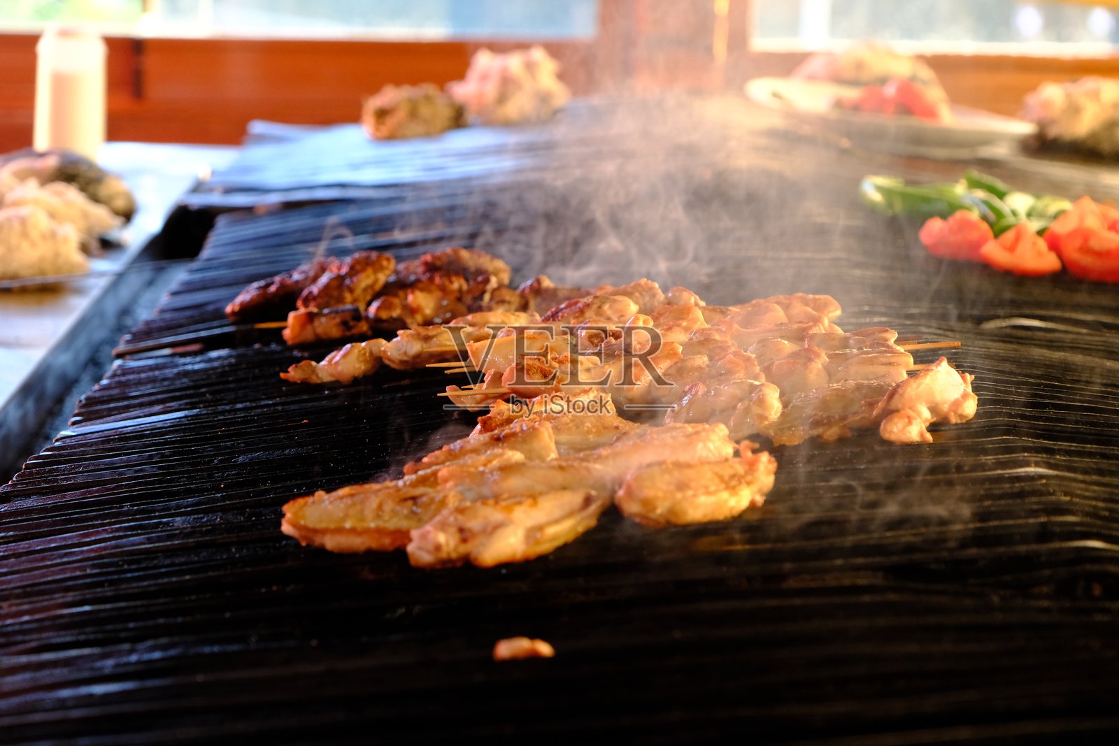 在肉类餐厅，鸡翅、鸡肉串和肉丸在烧烤上炸制和熏制。照片摄影图片