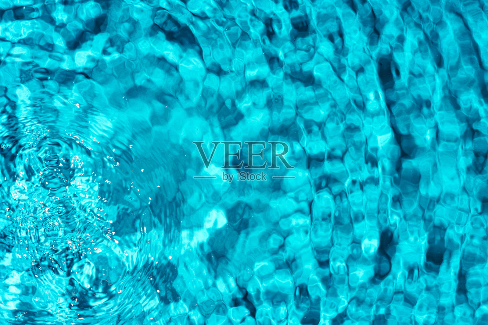 清澈的绿松石色泳池水在阳光下闪烁，泛起轻柔的涟漪照片摄影图片