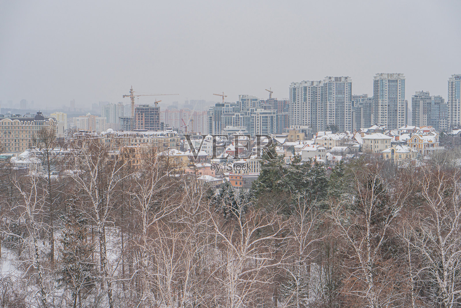 一幅彩色照片,展示了一个城市景观,雪覆盖的树木和建筑,展现了许多可能是住宅或商业的高层建筑 - 乌克兰基辅 2024年1月14日照片摄影图片