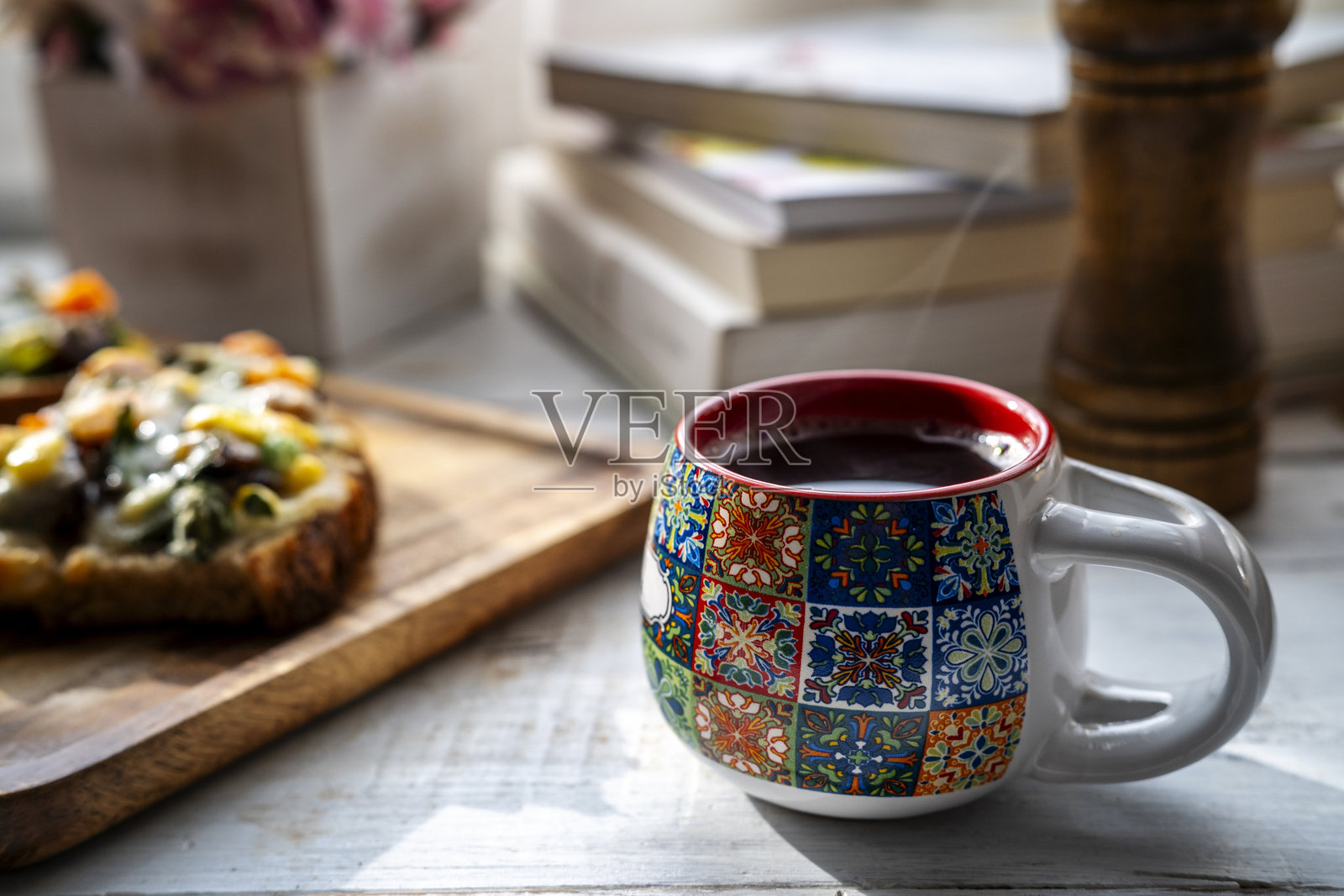 阳光下桌子上的咖啡、吐司和书籍照片摄影图片