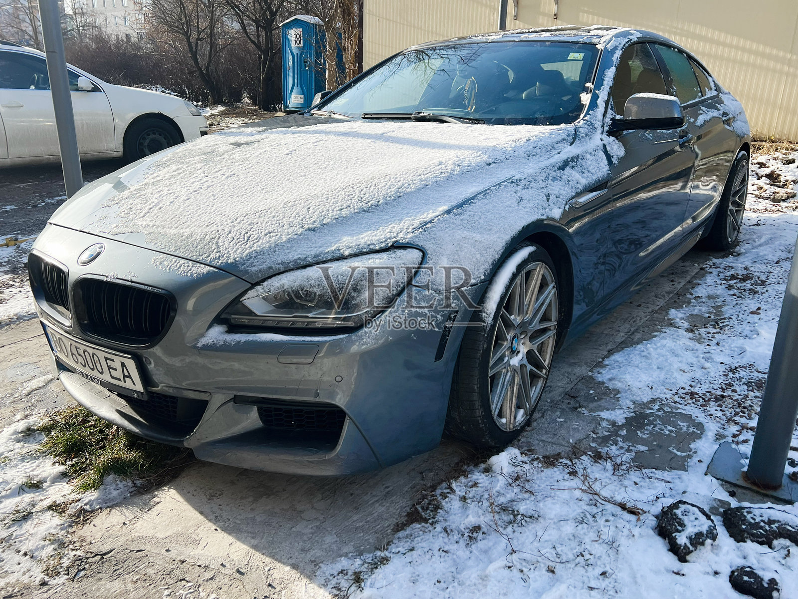 冬季户外停放的灰色豪华宝马6系（F12）轿跑，车身覆盖着雪。照片摄影图片