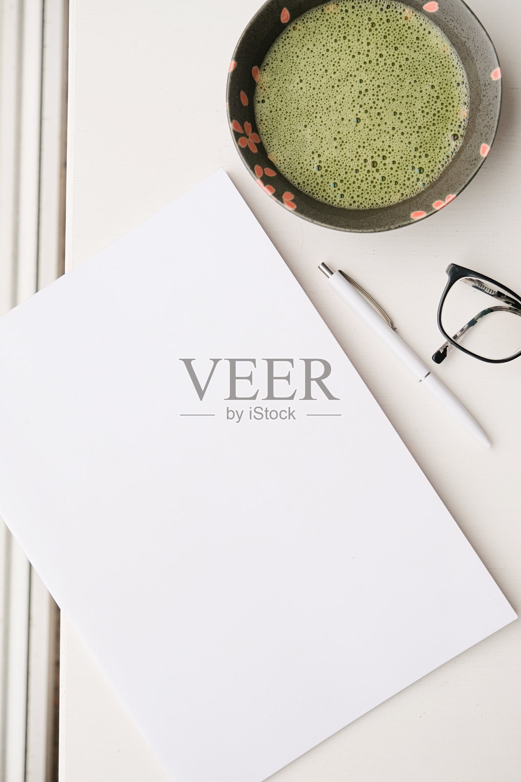 咖啡桌上放着空白杂志模型，旁边有绿茶抹茶，窗边光线明亮。照片摄影图片