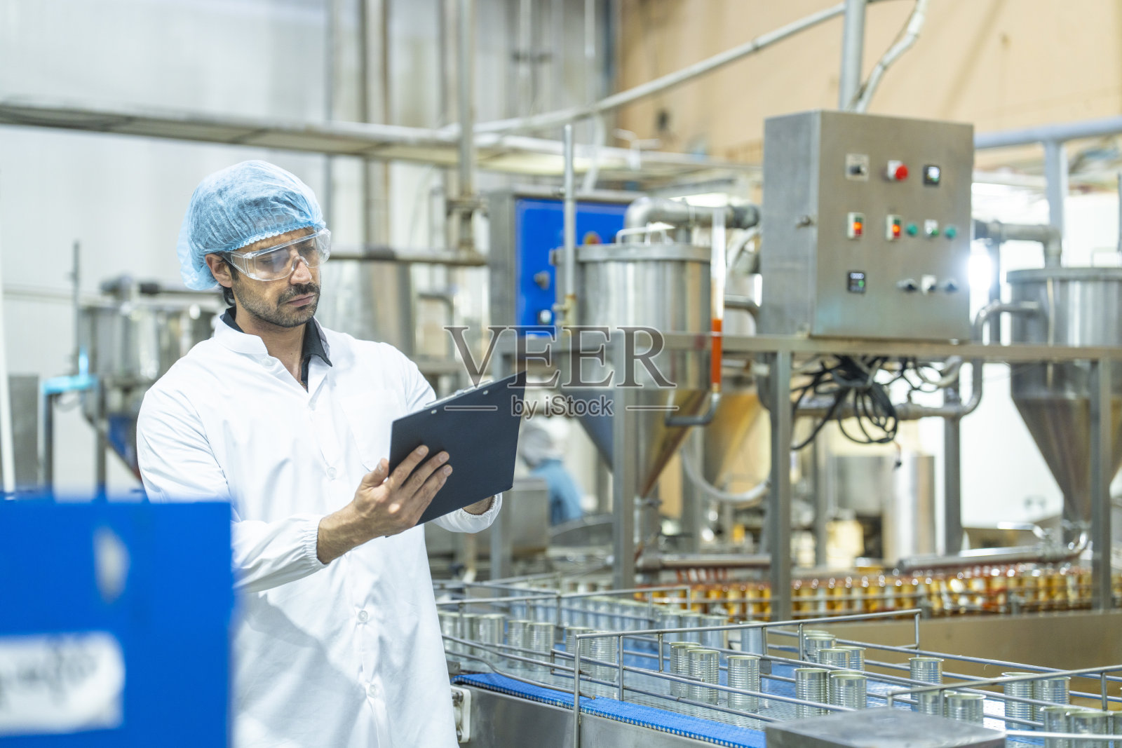 穿着整洁制服的工厂技术人员正在对产品进行详细检查，展示了质量保证、对细节的关注以及遵守安全和制造标准。照片摄影图片