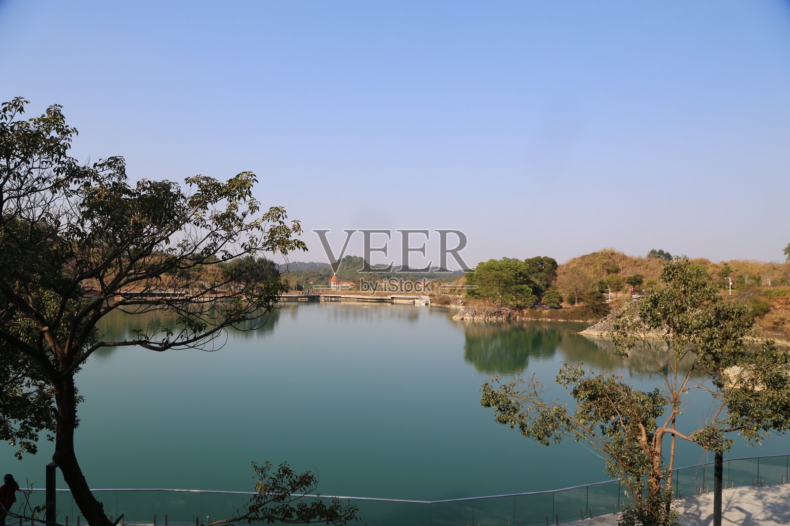 湖泊的全景，四周被树木和绿植环绕，背景是湛蓝的天空照片摄影图片