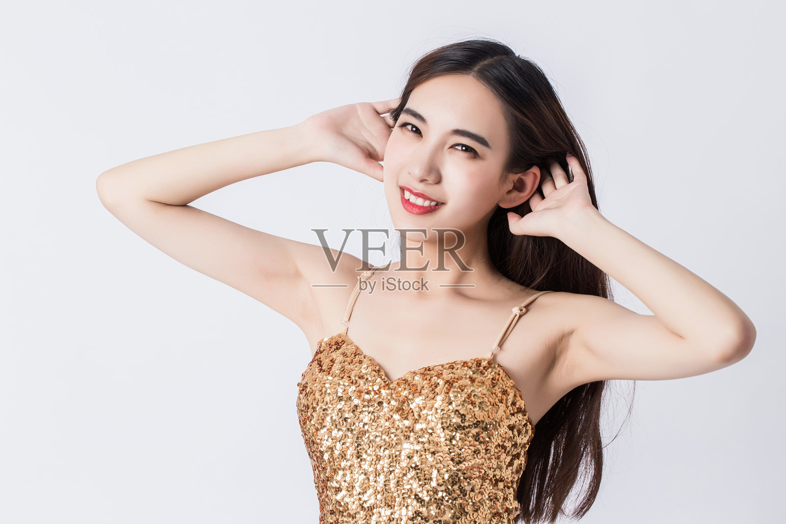 身穿金色长款晚礼服的美丽女性在白色背景前摆姿势照片摄影图片