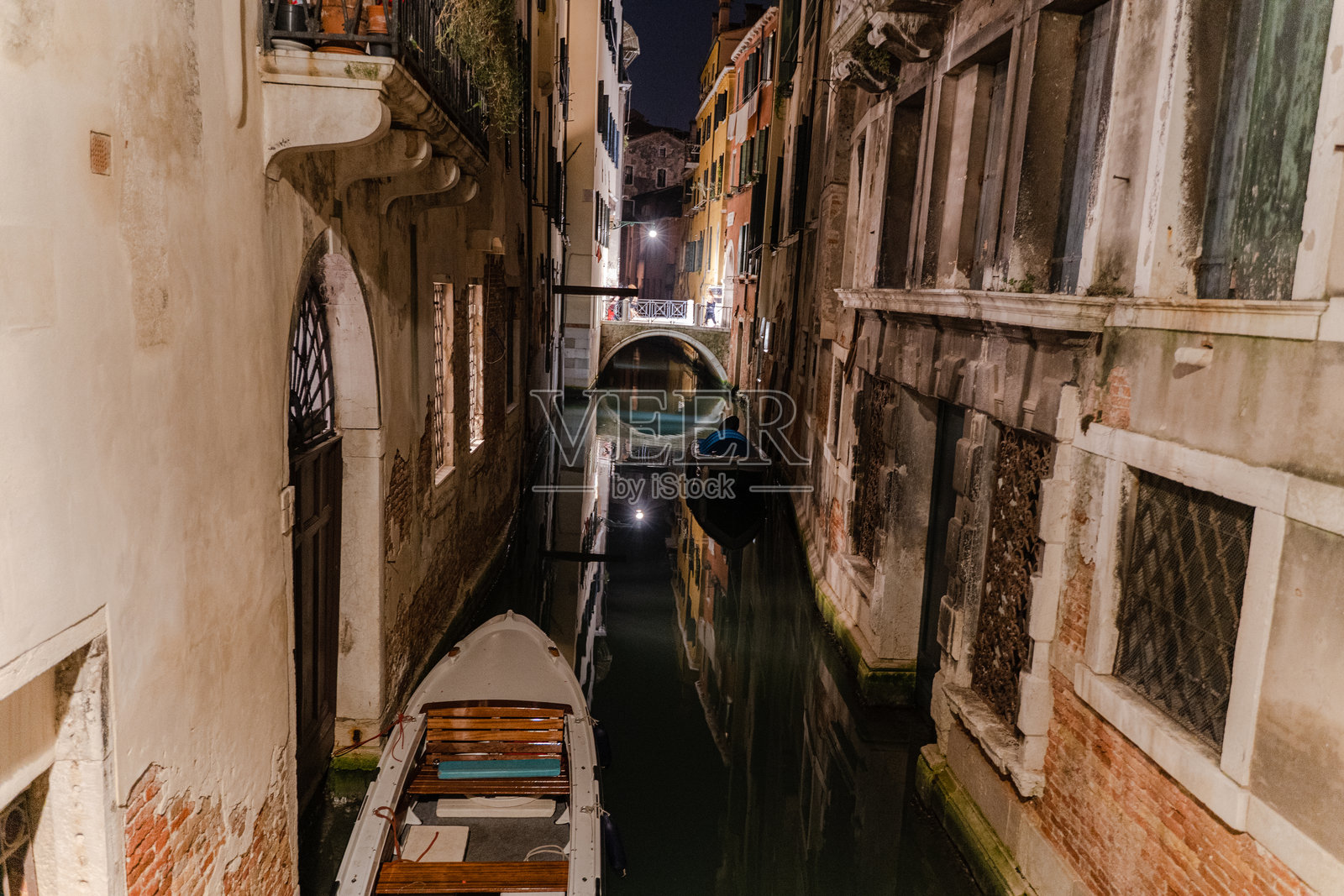 夜晚的威尼斯。人们在狭窄运河的桥上漫步。照片摄影图片