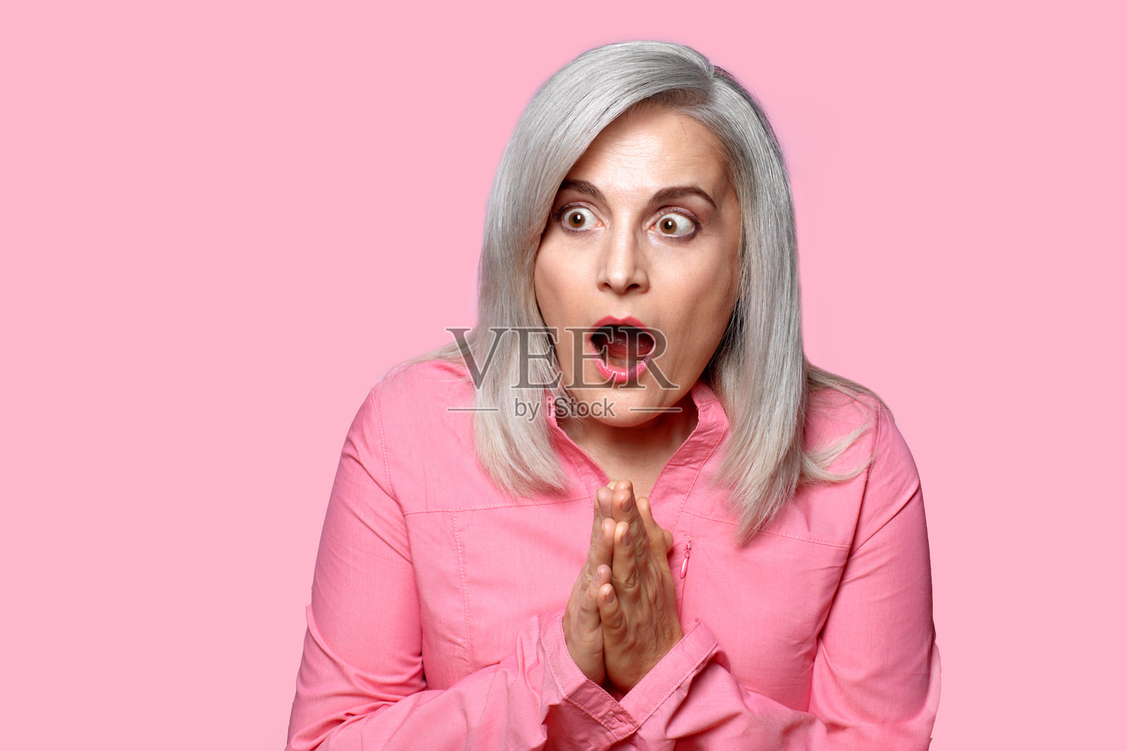 一位女性用手势表达惊讶和恐惧。粉色背景下的特写肖像。照片摄影图片
