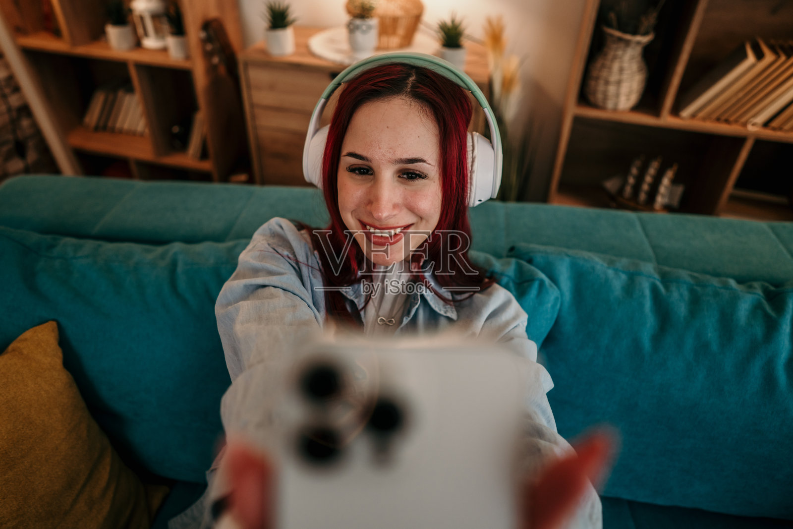 女人坐在青绿色沙发上自拍。照片摄影图片