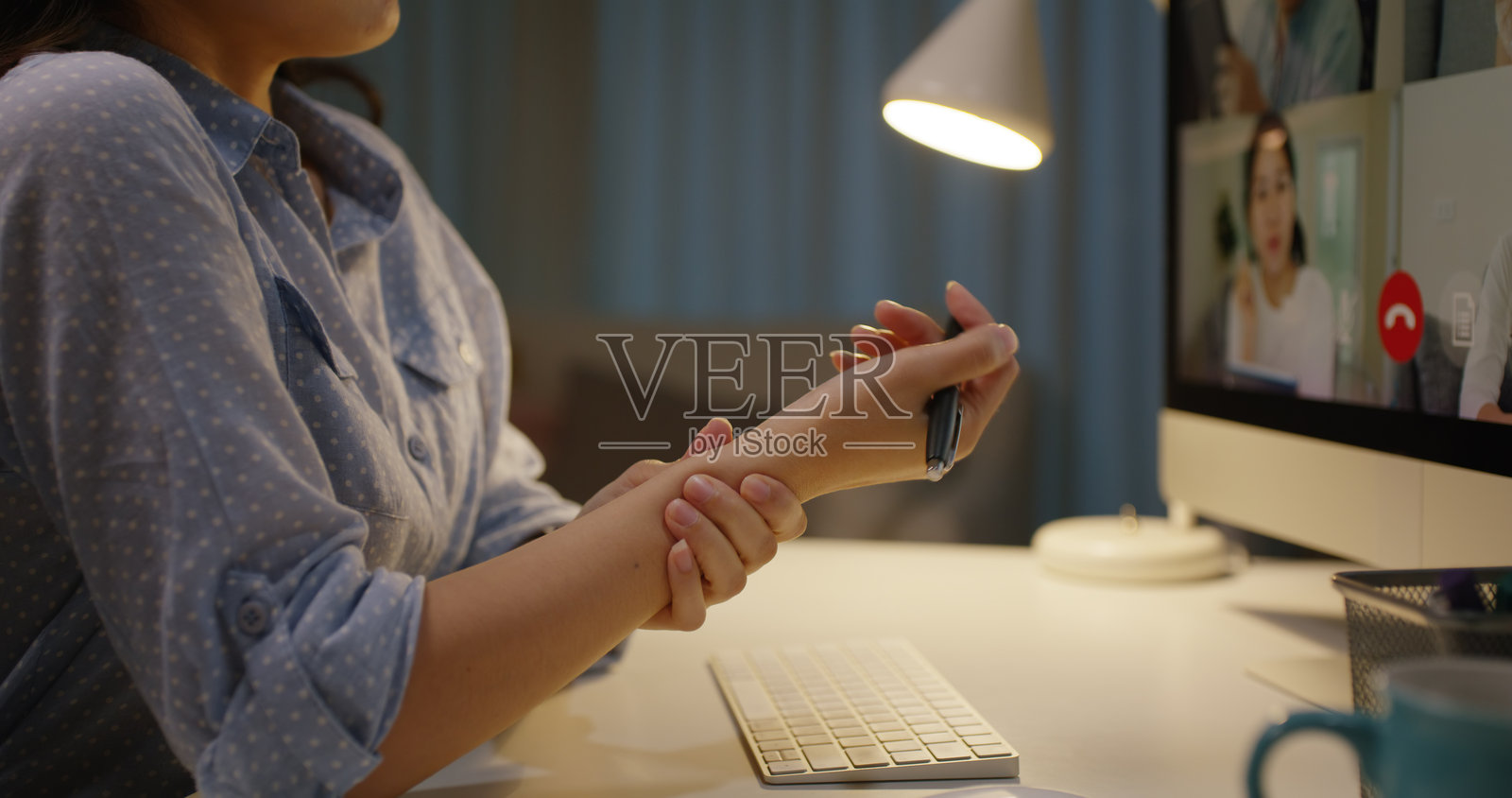 年轻的亚洲女性在深夜忙碌，进行视频通话，缓解因长时间坐在电脑前而导致的颈部僵硬和疼痛，面临慢性疲劳和办公室综合症的困扰。照片摄影图片