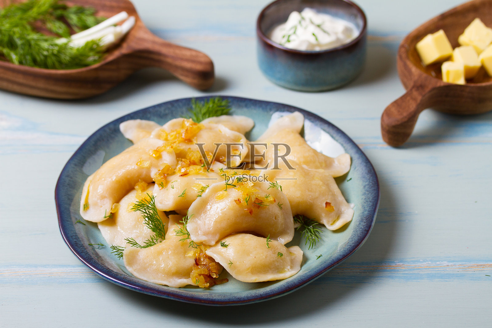 土豆泥馅饼。饺子，瓦伦基，皮罗戈，皮罗希 - 蓝色盘子上的馅饼，背景为绿色蓝色木材。照片摄影图片