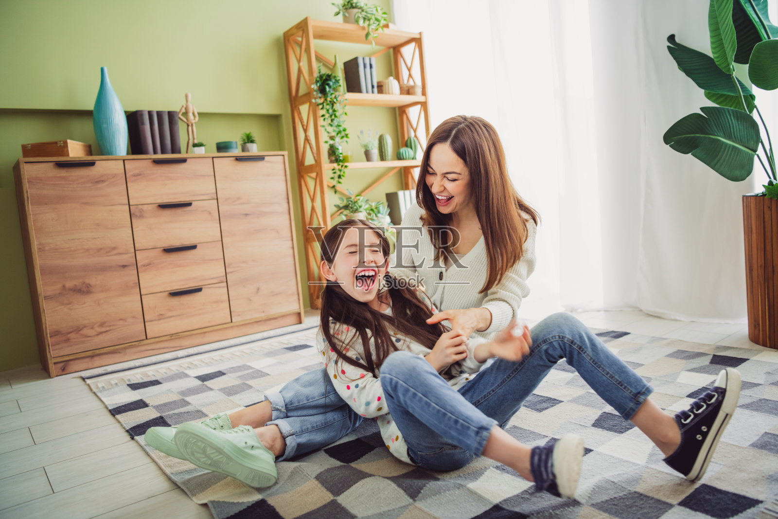 快乐的年轻母亲在舒适的客厅里与女儿玩耍，享受自然光下的美好时光照片摄影图片