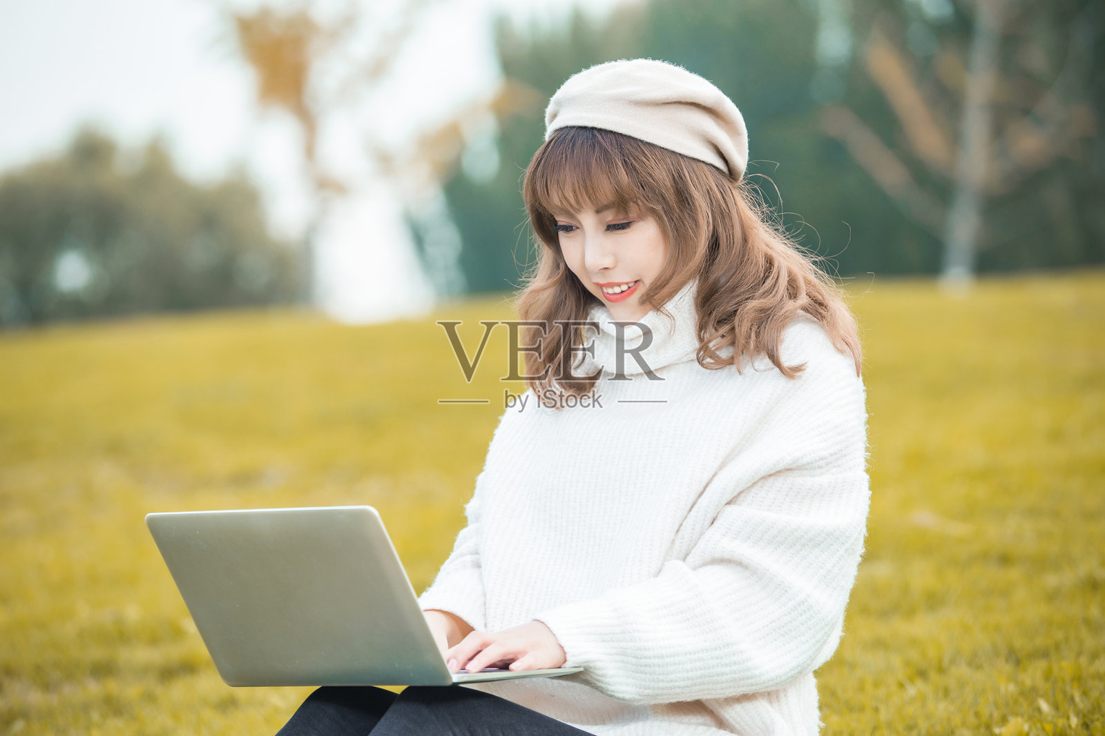 在公园里使用笔记本电脑的快乐女性肖像照片摄影图片