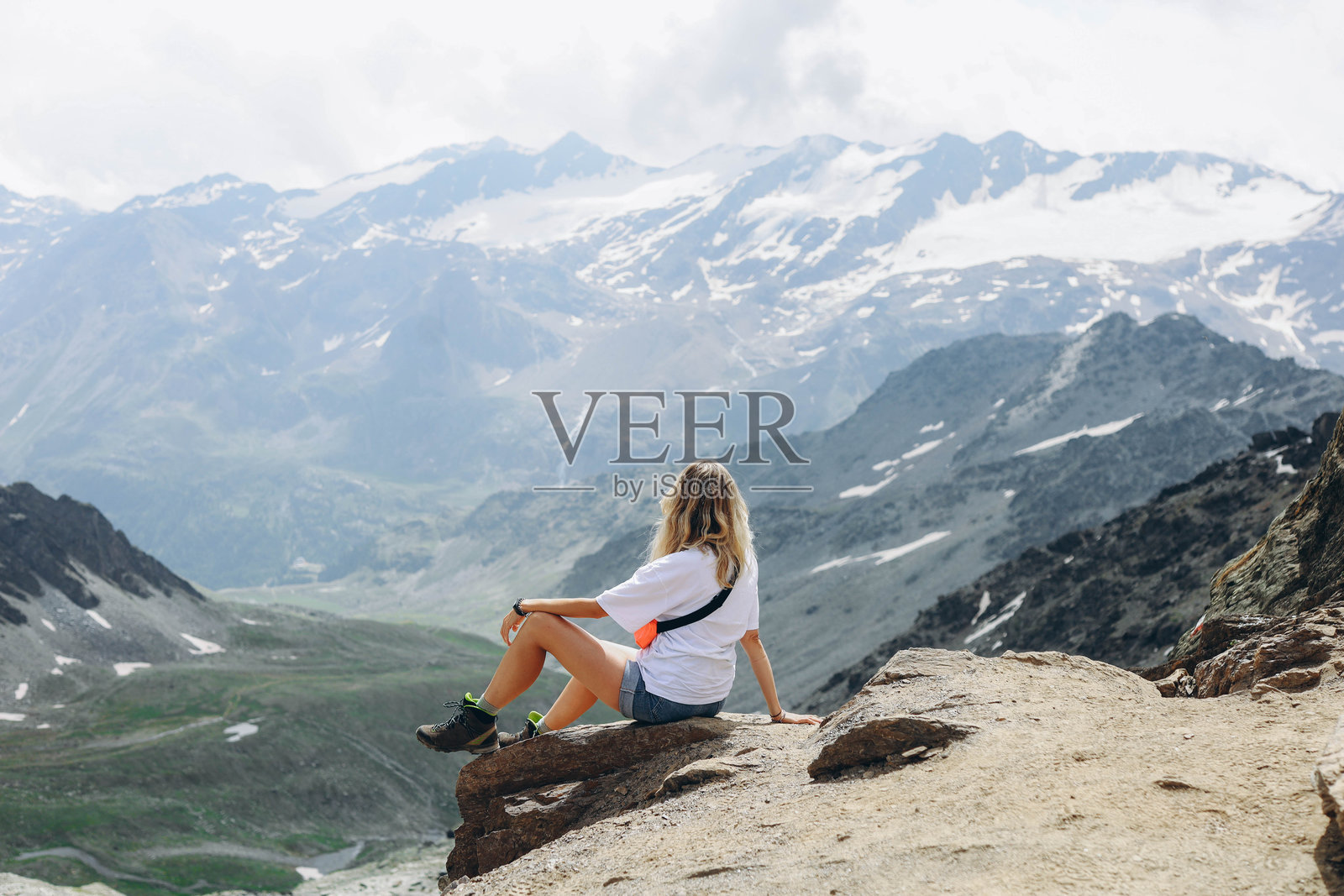 一位年轻女性坐在山顶，欣赏从峰顶俯瞰的壮丽景色照片摄影图片