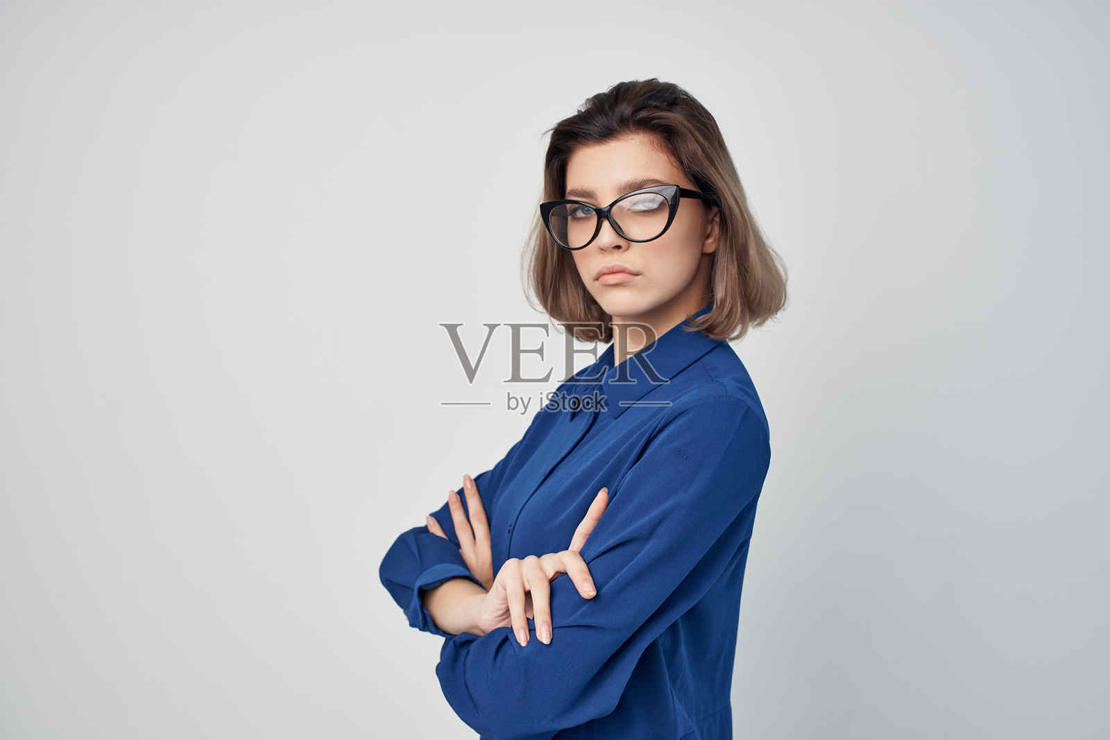 穿着蓝色衬衫、戴着眼镜的优雅时尚女性摆姿势照片摄影图片