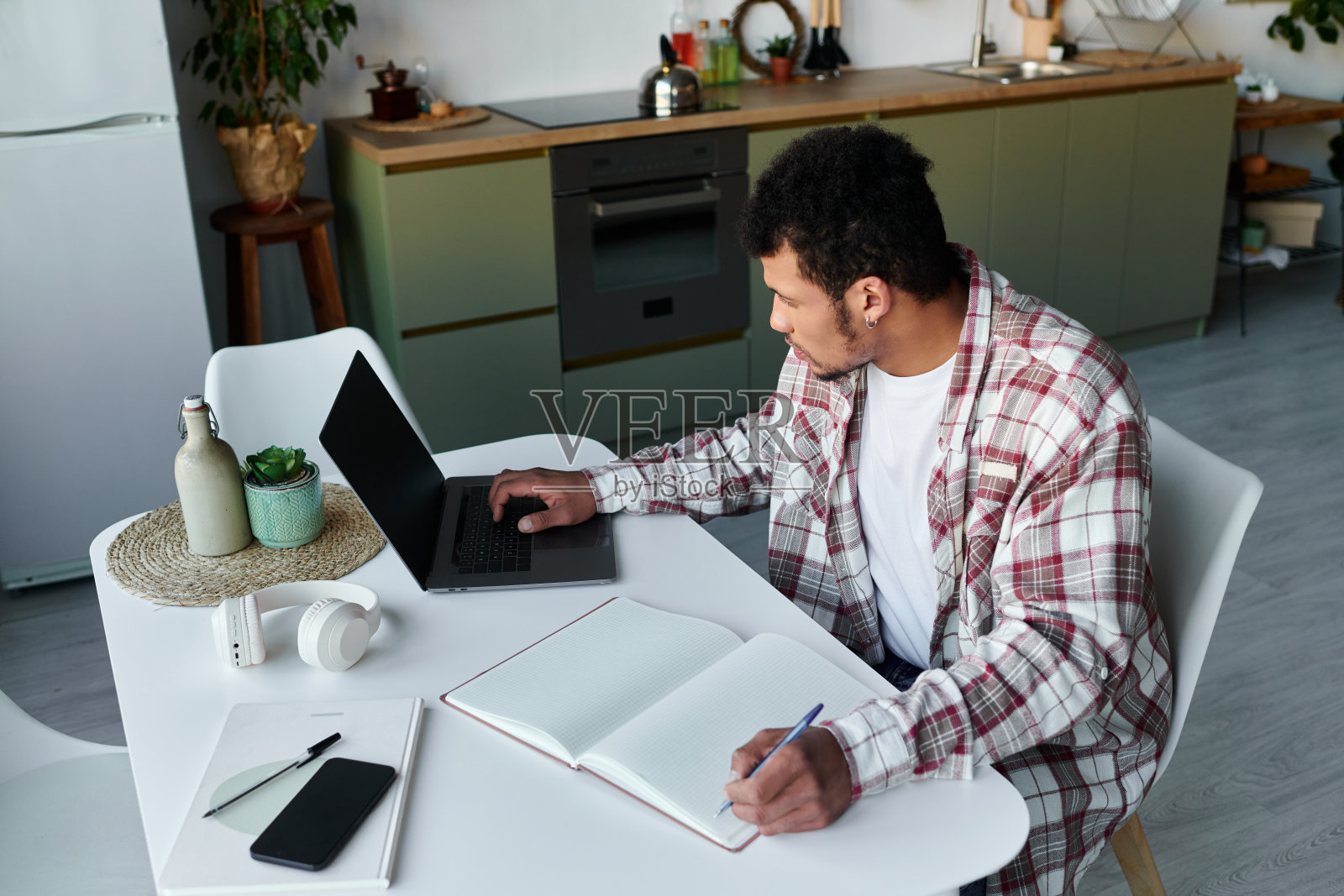 卷发年轻男子专注于工作，身处时尚现代的公寓环境中照片摄影图片