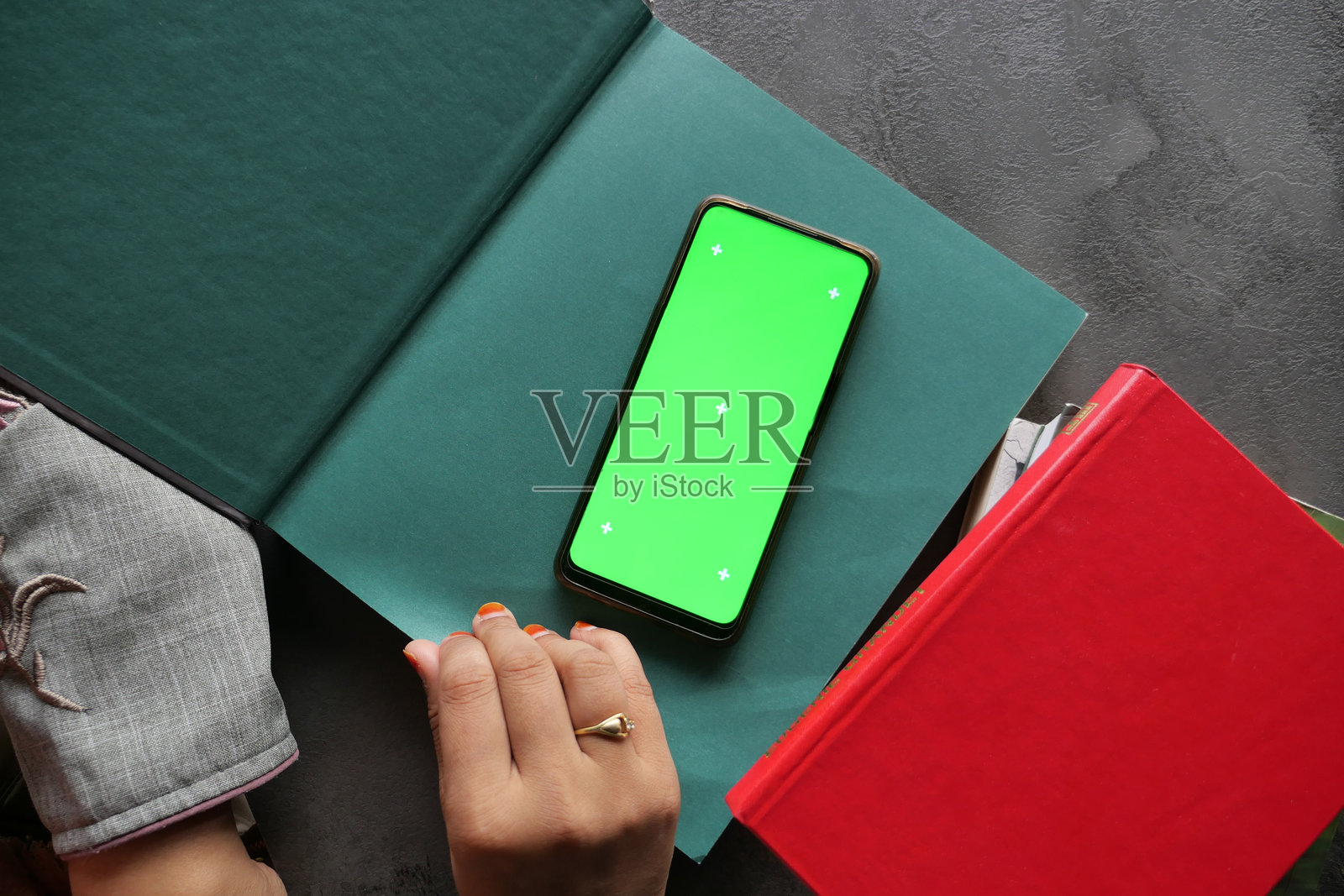 一部智能手机放在书本上，背景为生动的绿色，适合创意样机展示。照片摄影图片