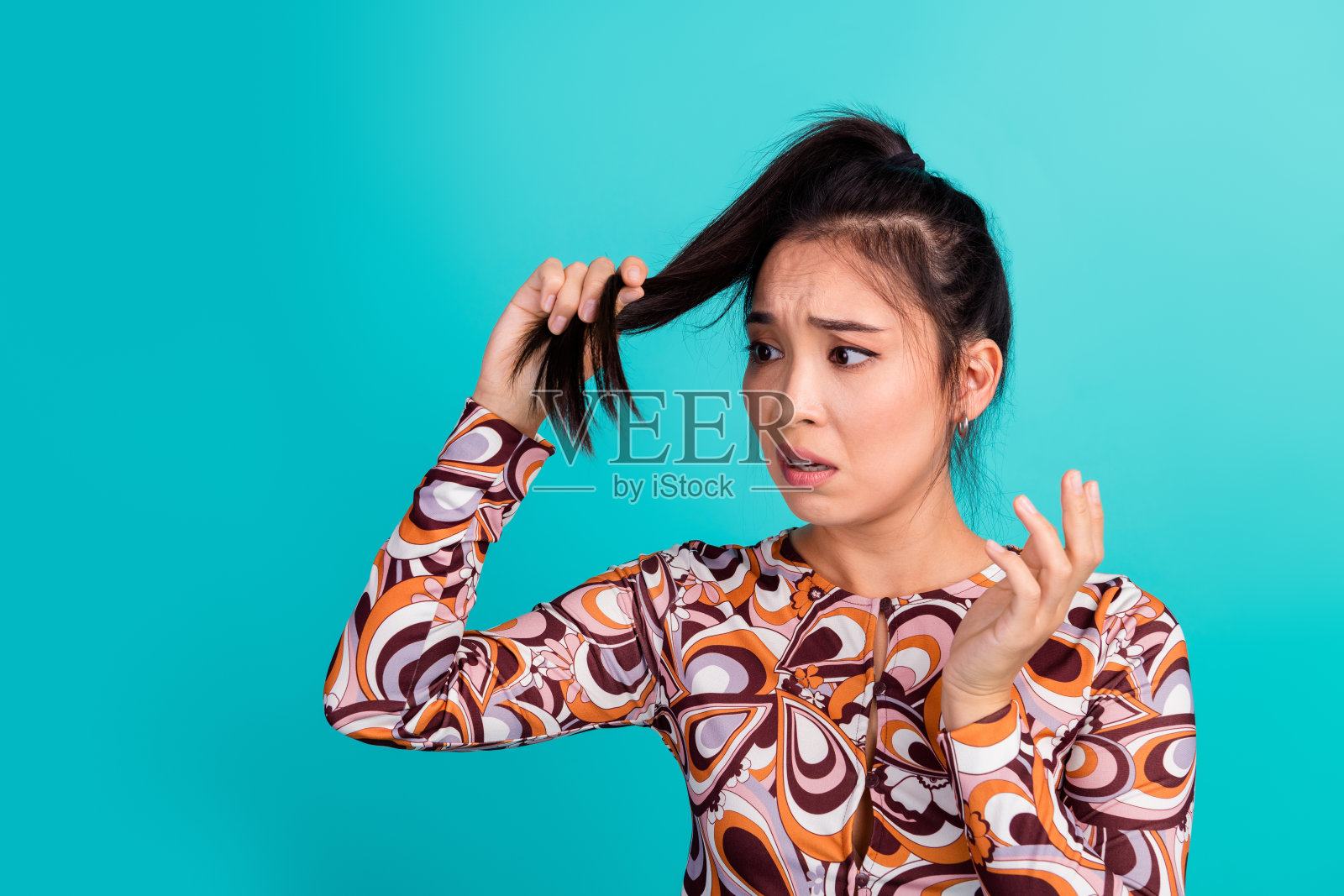 可爱的年轻女士的照片肖像，困惑而紧张的表情，时尚的彩色服装，背景为青色。照片摄影图片