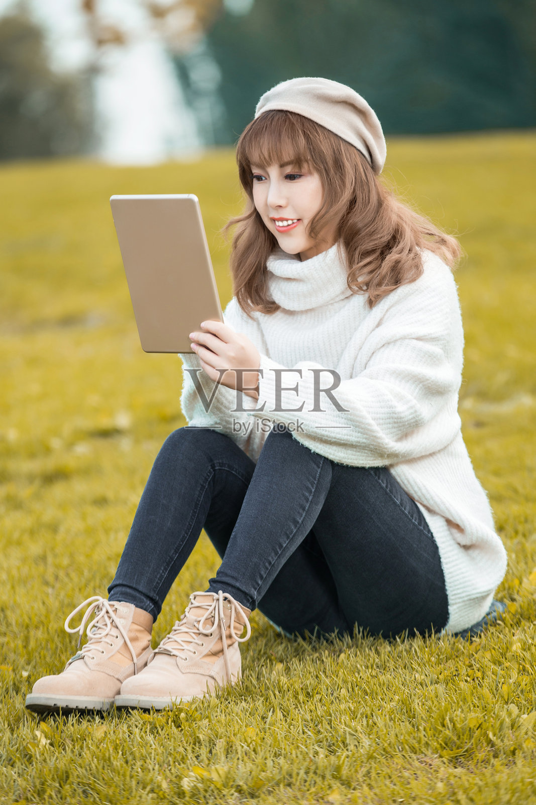 公园里一位快乐的女性正在使用平板电脑照片摄影图片