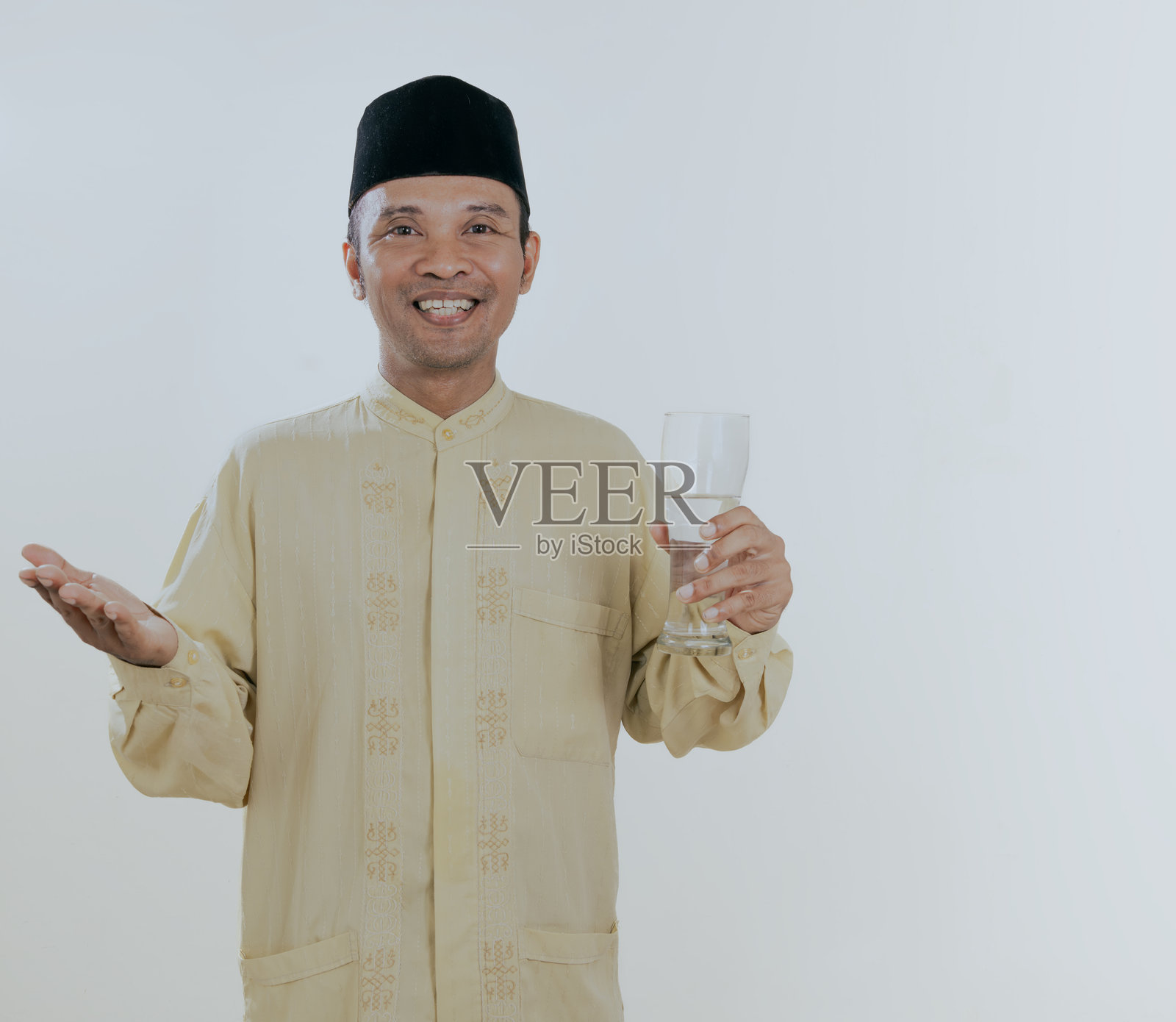 微笑的穆斯林亚洲男子在喝水，准备打破禁食。照片摄影图片