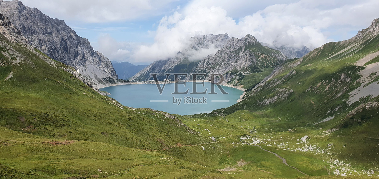 宁静的山间湖泊被郁郁葱葱的山丘环绕。照片摄影图片