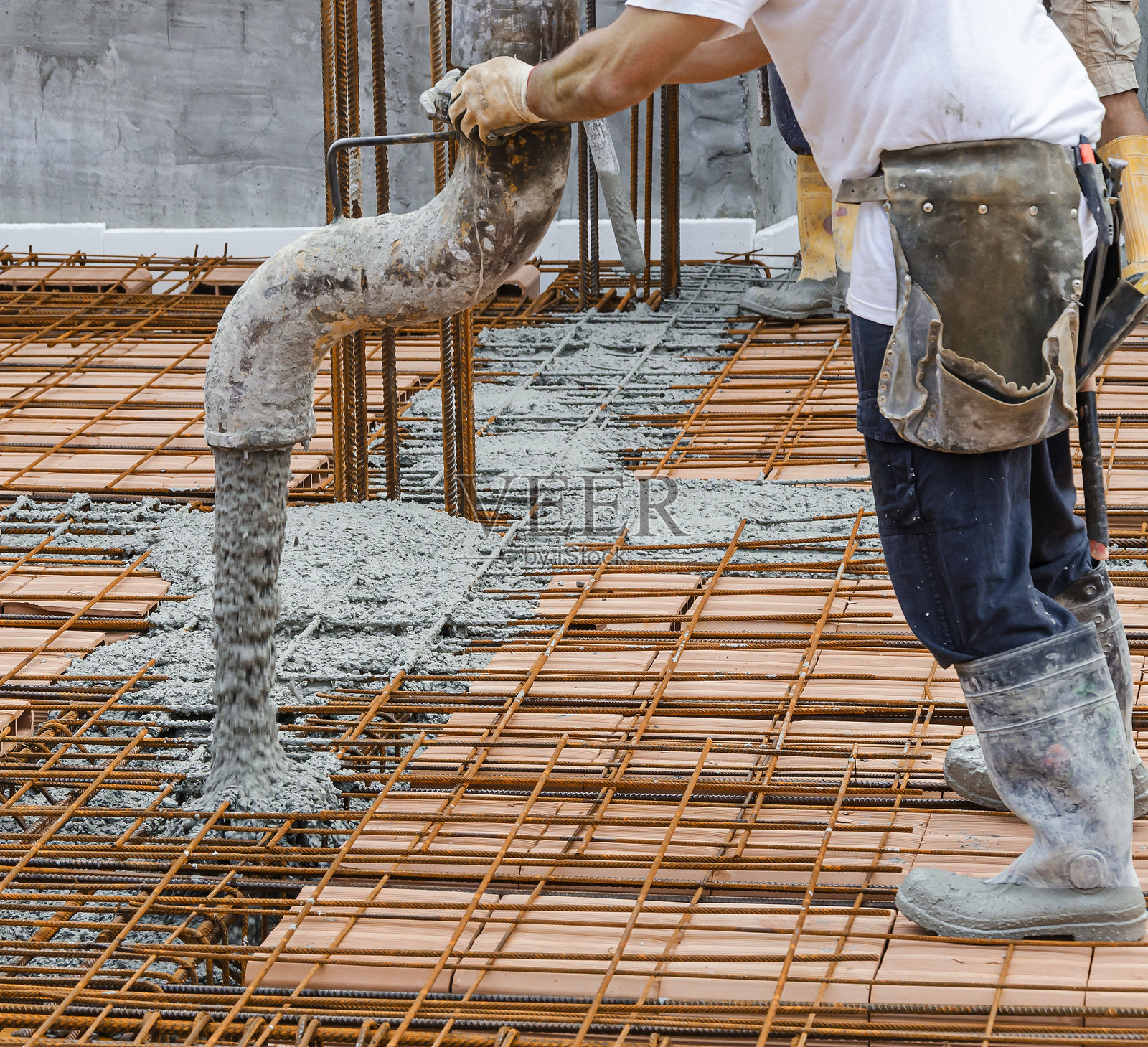 穿橙色衬衫的工人在建筑工地上浇筑混凝土照片摄影图片