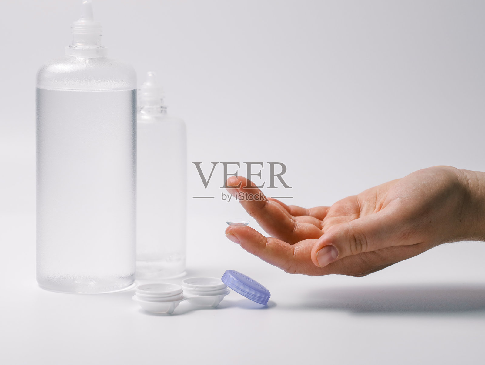 手握隐形眼镜和打开的镜片盒，背景为白色。眼部护理、卫生和视力矫正的概念。照片摄影图片