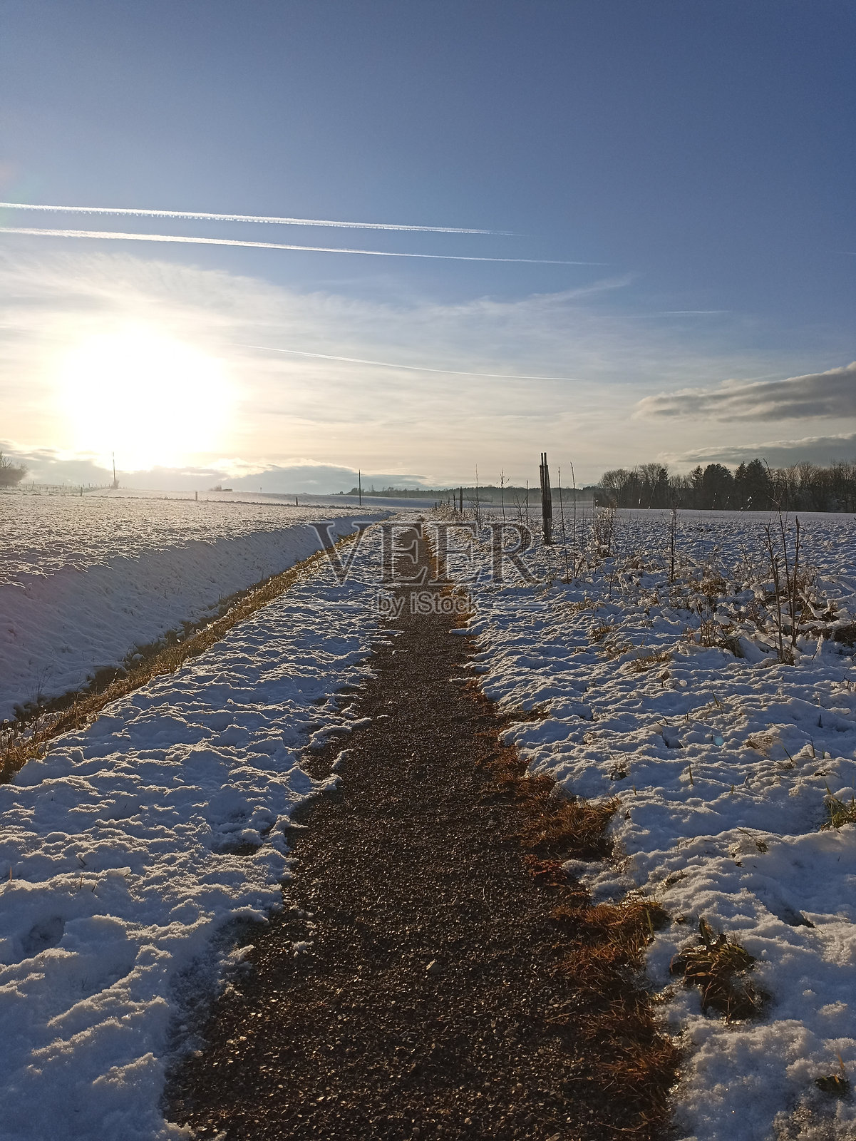 乡间小路穿越雪覆盖 的风景，夕阳西下照片摄影图片
