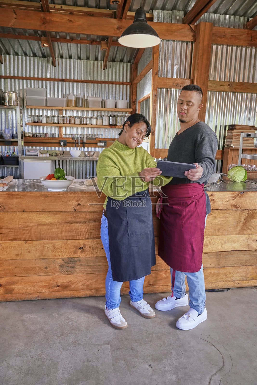 服务员和女服务员在餐厅柜台前站着，手持平板电脑交谈。照片摄影图片