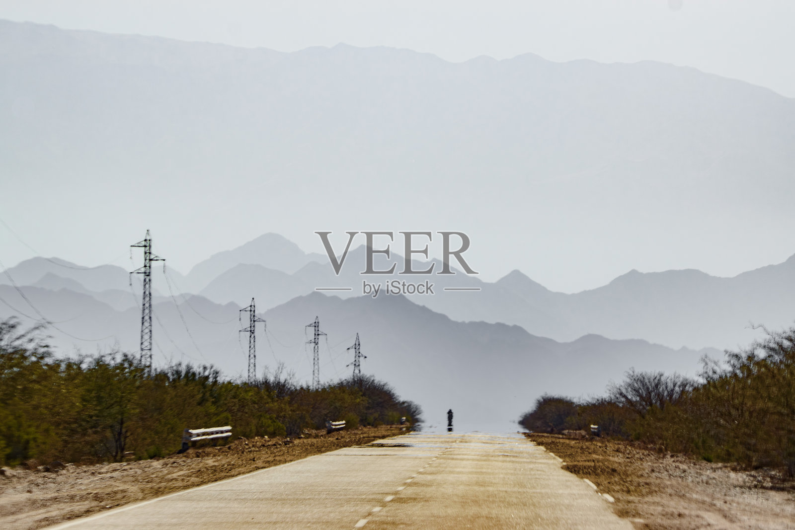 阿根廷卡塔马卡的46号公路上远处的一辆摩托车。照片摄影图片