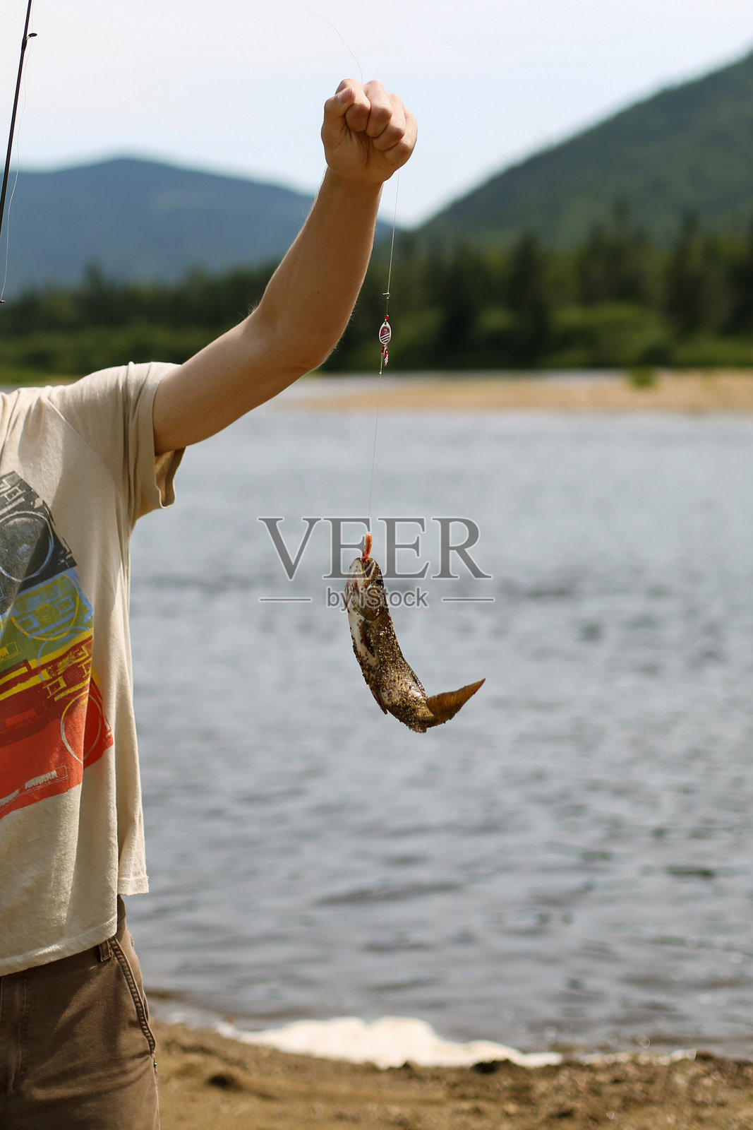 男子展示新鲜捕获的河鳟鱼照片摄影图片