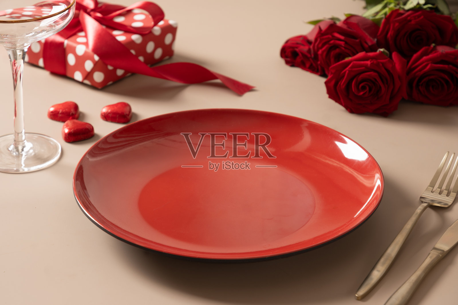 情人节的桌面布置，红色餐盘、红酒和玫瑰。浪漫晚餐。照片摄影图片