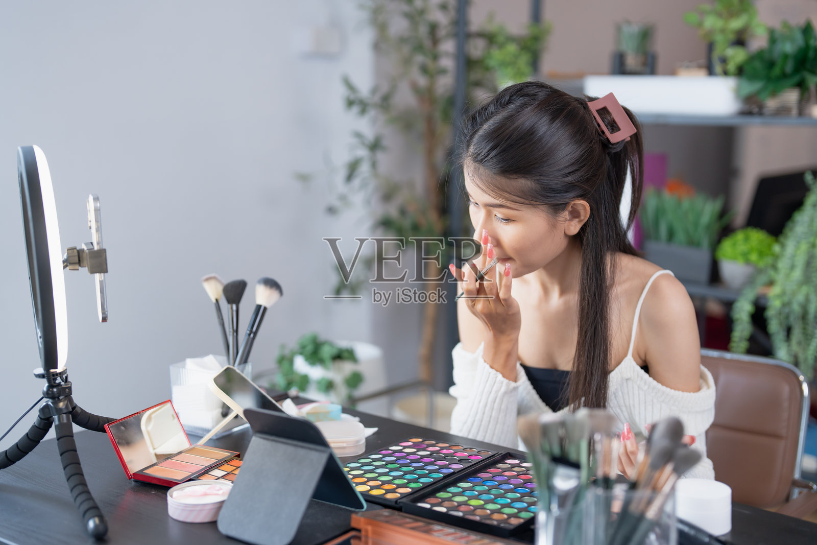 亚洲女性美容博主化妆师在智能手机上进行直播化妆教程，分享至社交媒体照片摄影图片