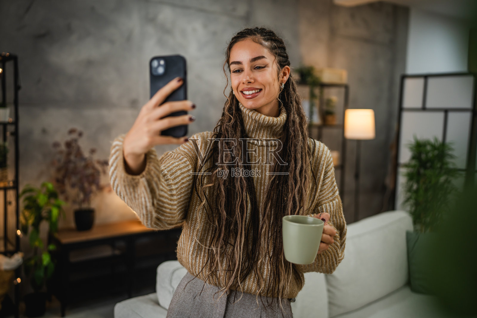 美丽微笑的年轻女性在家中用杯子拍摄自拍照照片摄影图片