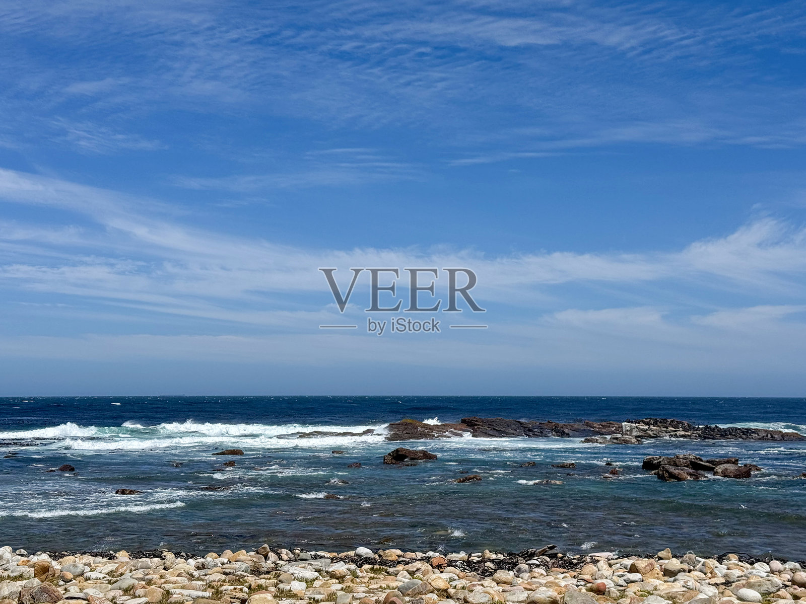 海浪拍打在岩石海岸上，蓝天白云相伴照片摄影图片