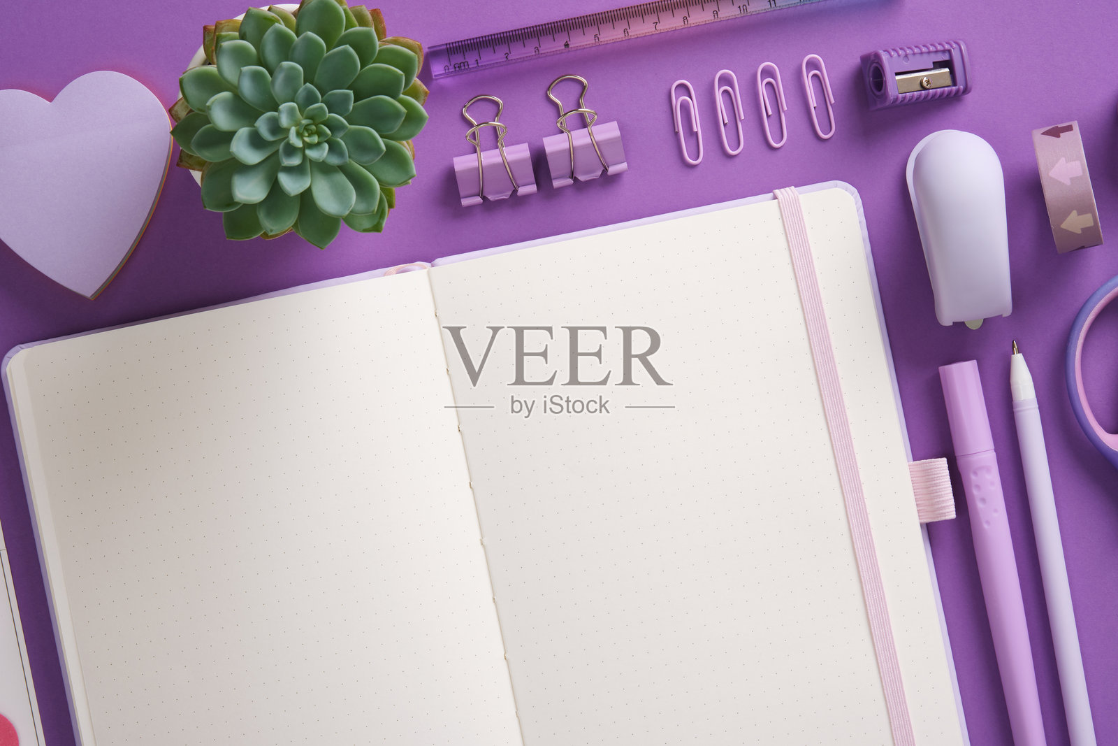 紫色主题的打开的记事本和文具，马克笔，订书机，尺子，橡皮擦，图钉，夹子。留出空间供您填写文本。照片摄影图片