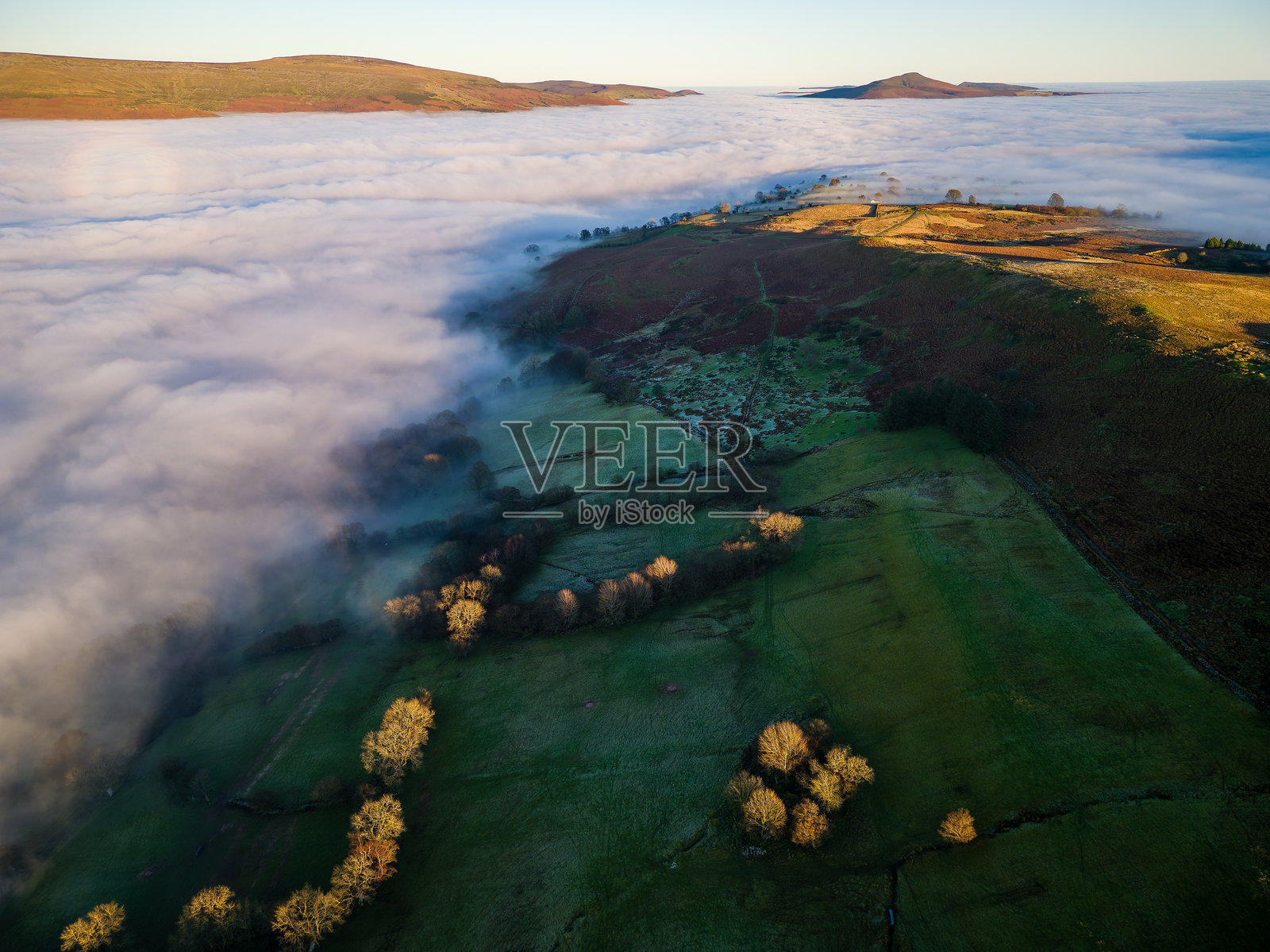无人机视角下的乡村山谷，浓雾弥漫，背后是高耸的山丘。照片摄影图片