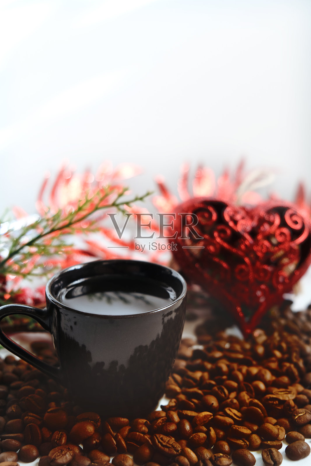 黑色咖啡杯与圣诞装饰，红色心形，充满爱意。新鲜采摘的咖啡豆和香气四溢的咖啡。冬季假期。照片摄影图片