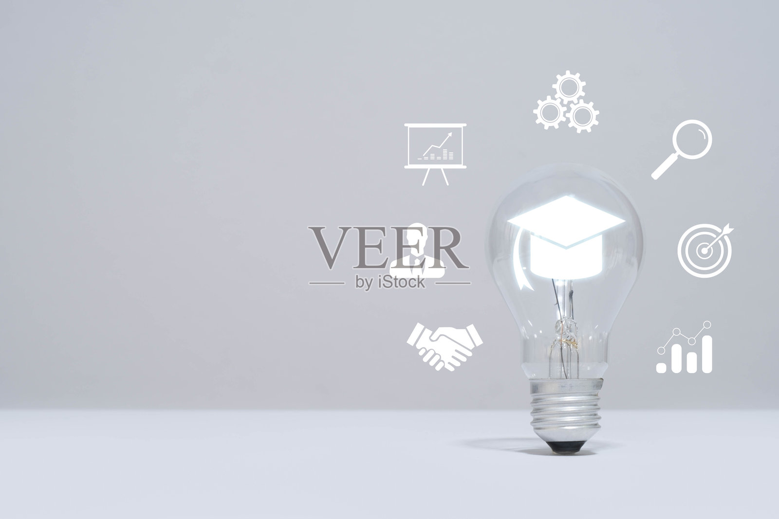 象征教育和创新的灯泡，周围环绕着各种图标，背景为灰色，象征着创意和成长。照片摄影图片