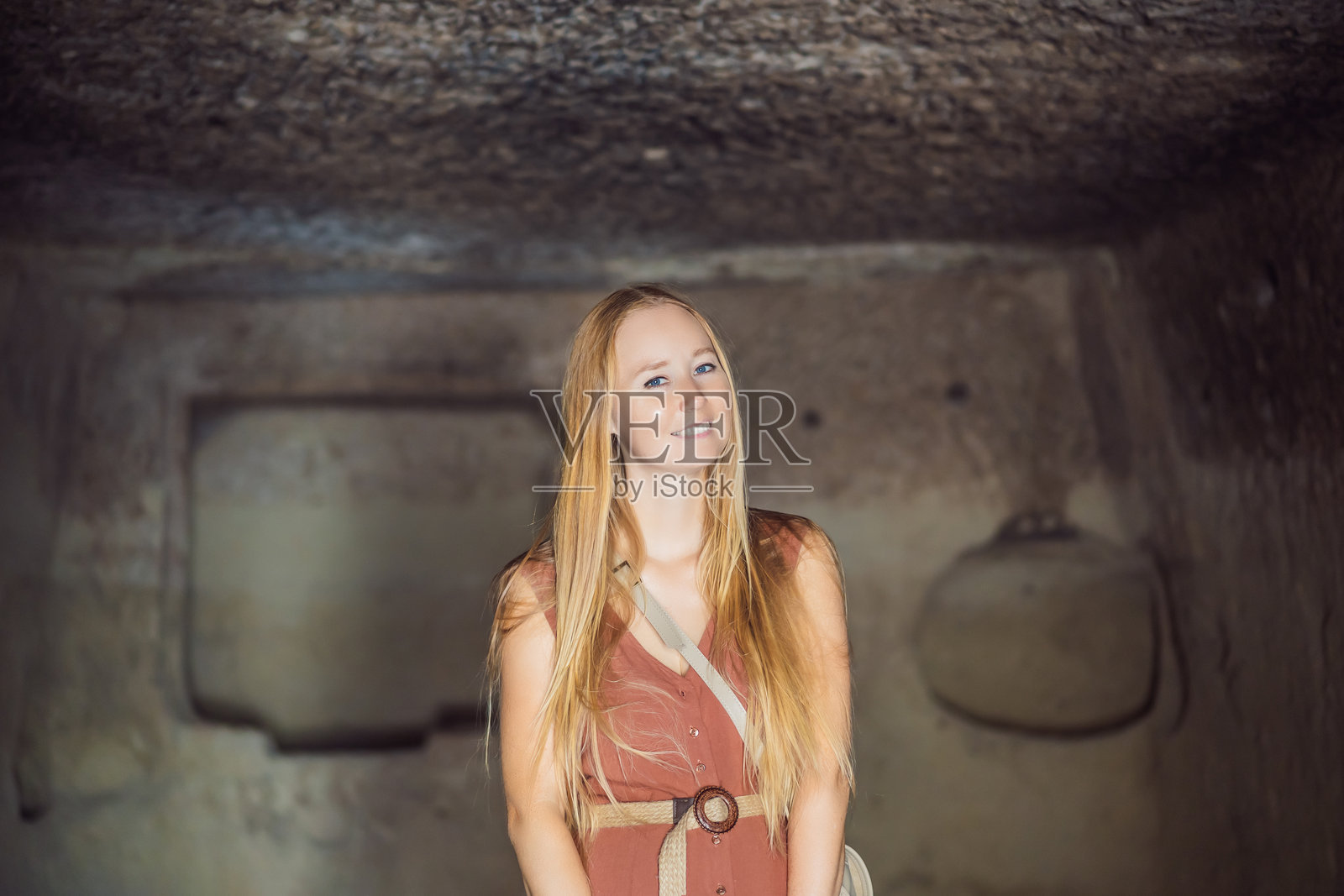 年轻女性在土耳其卡帕多奇亚的戈雷梅附近探索岩石形成和仙女洞穴的山谷照片摄影图片