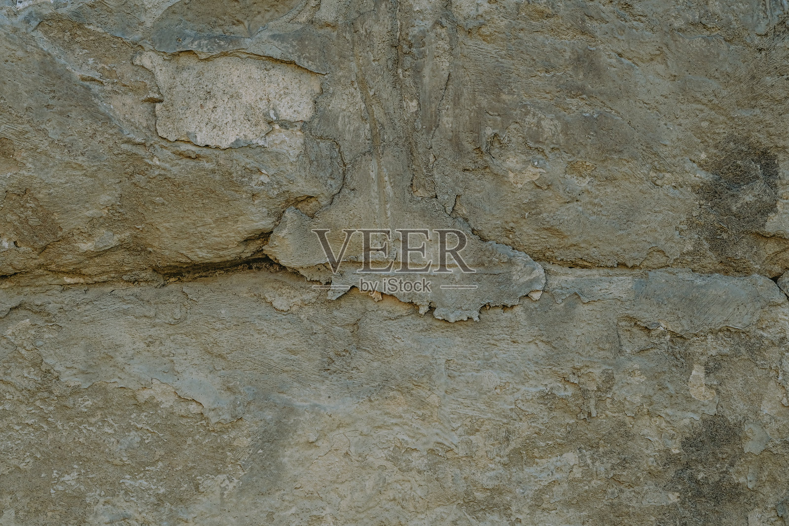 阳光下的风化石墙特写，展示了纹理和自然侵蚀的图案照片摄影图片